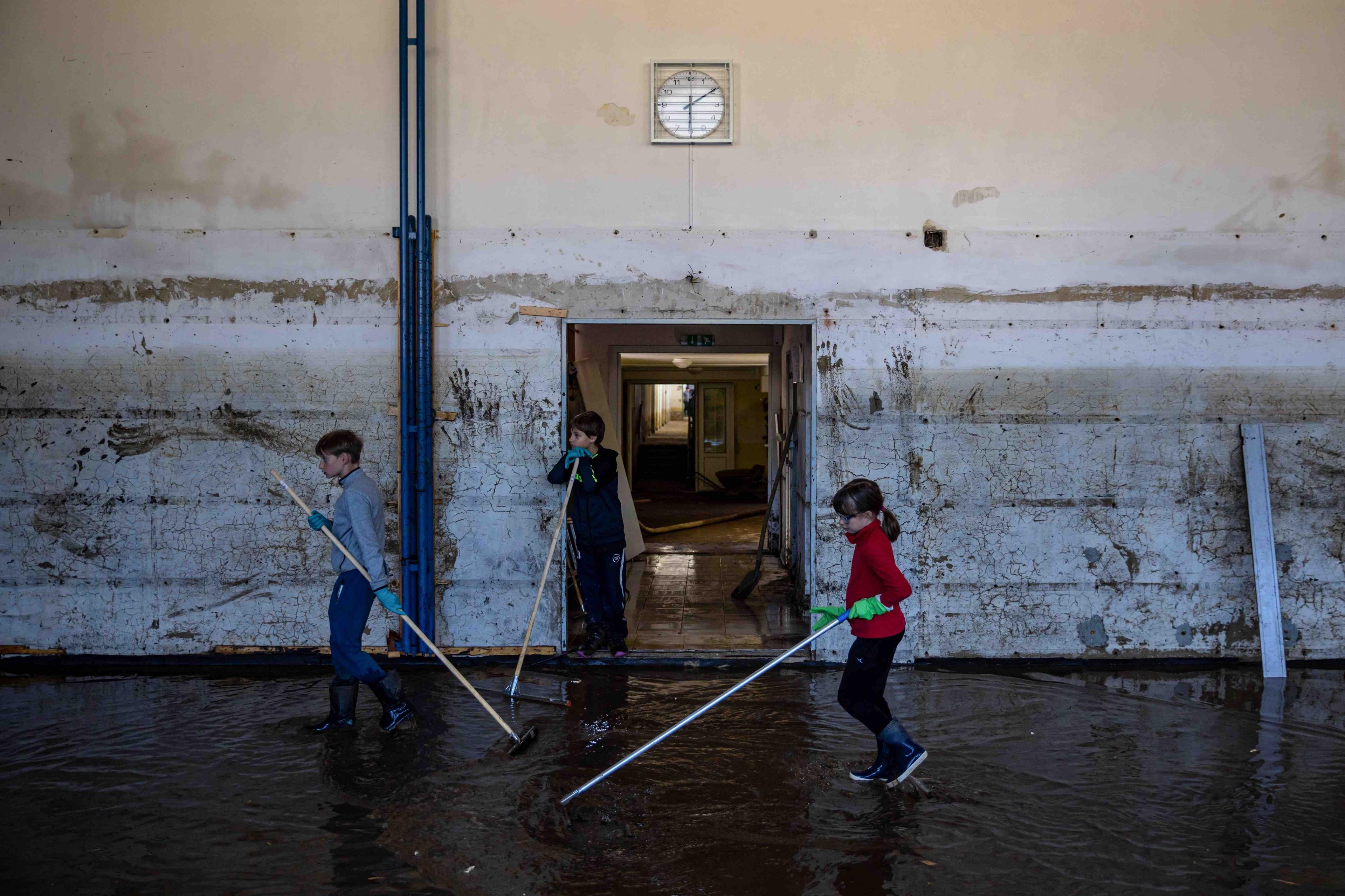 children with sticks cleaning flooded school hall