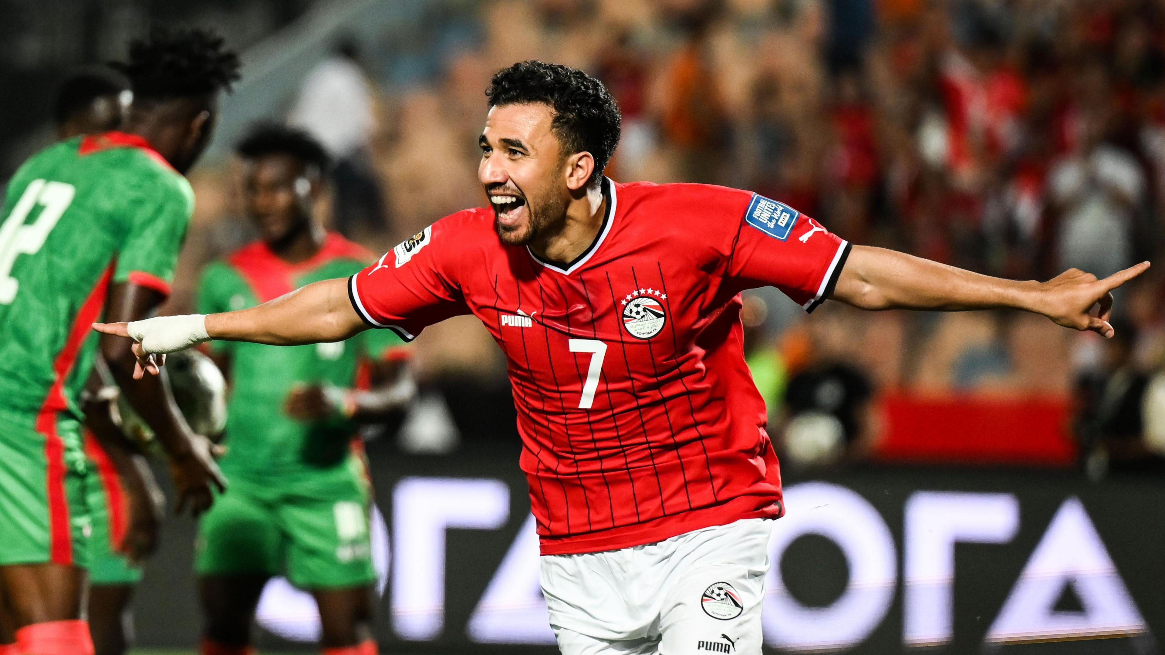 Egypt forward Trezeguet smiles and wheels away with his arms wide in celebration after scoring a goal