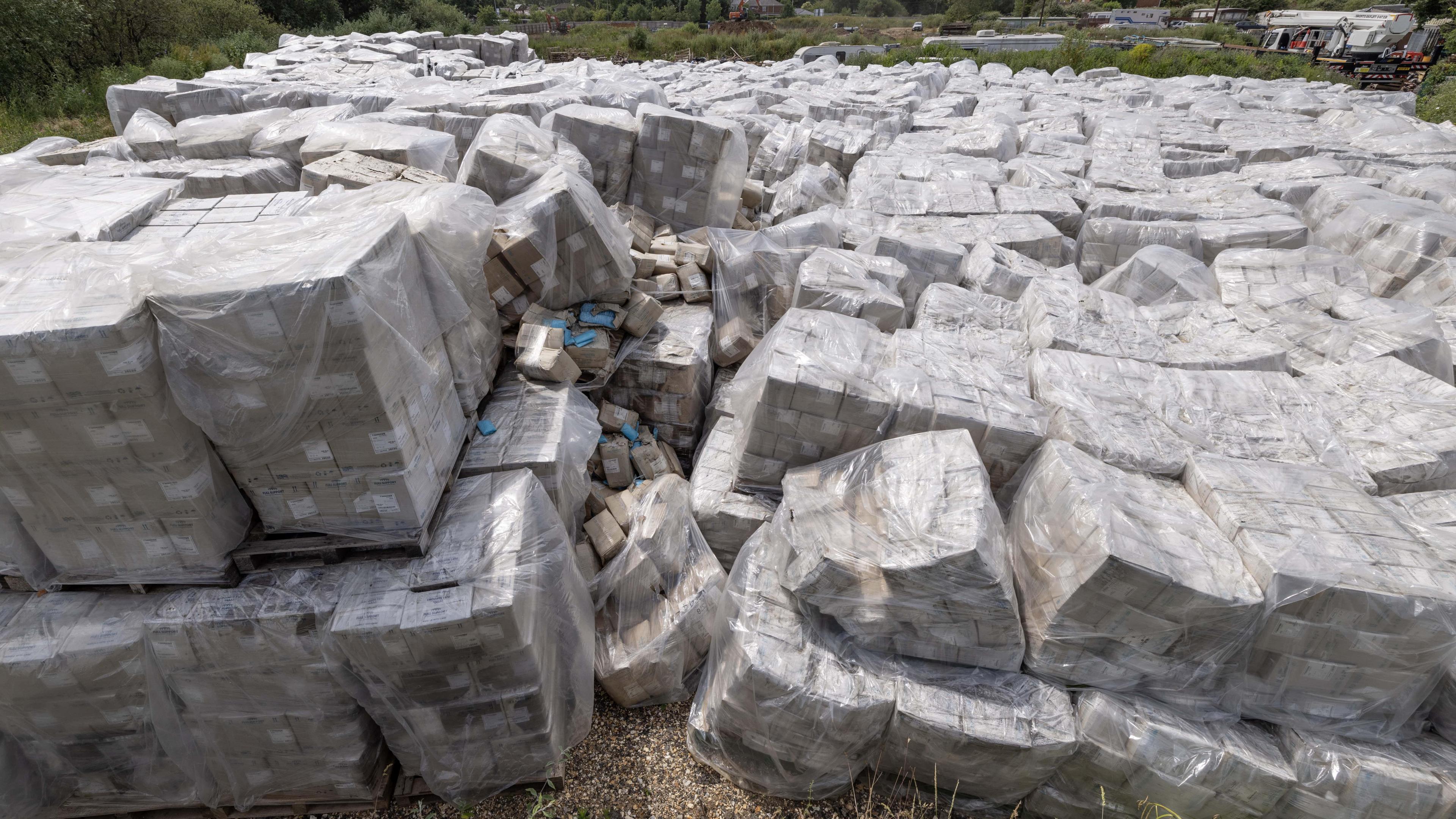 A large pile PPE packaged in boxes, and each box wrapped in plastic.