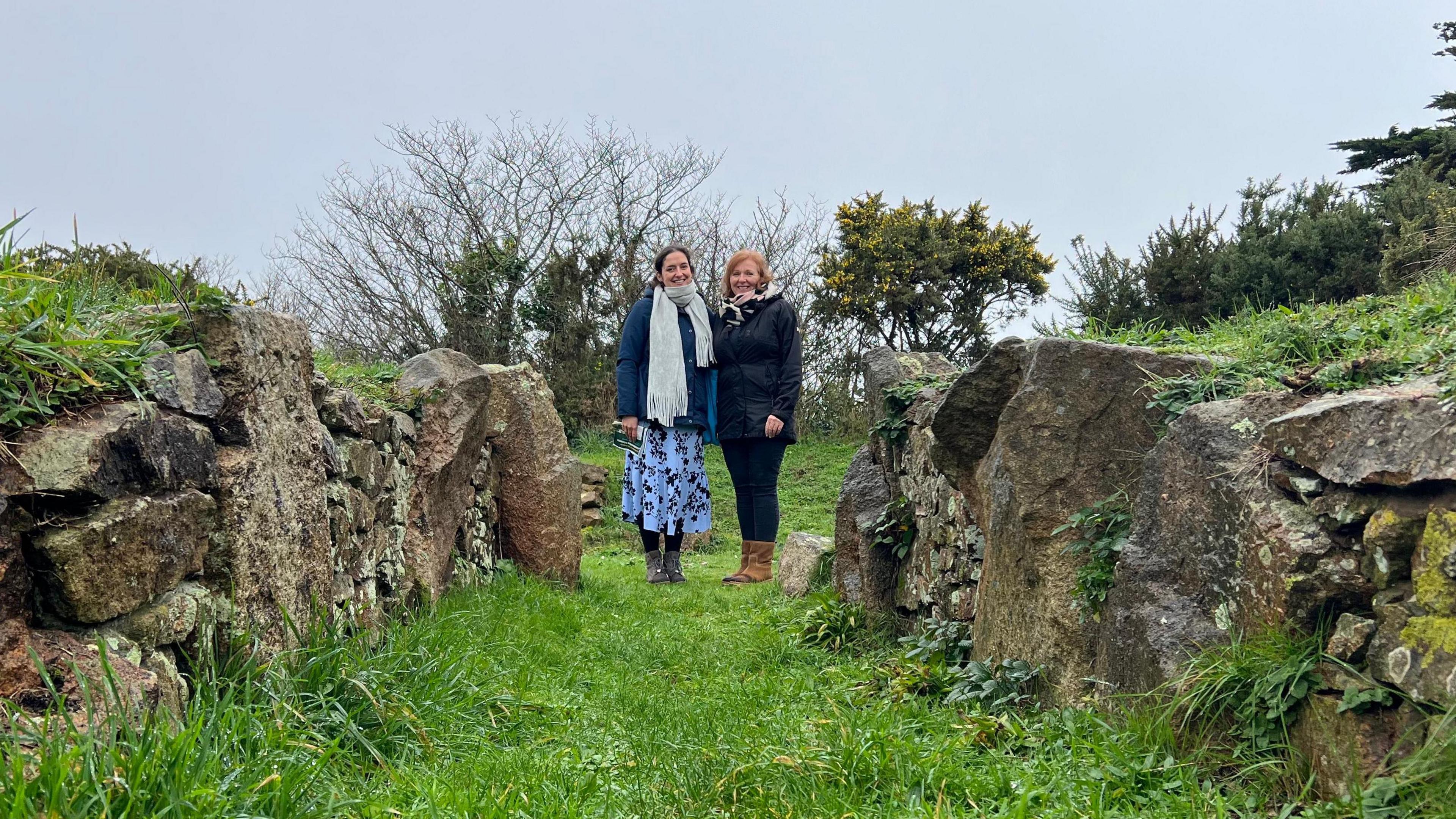 Two ladies stand in the entrance of a dolmen