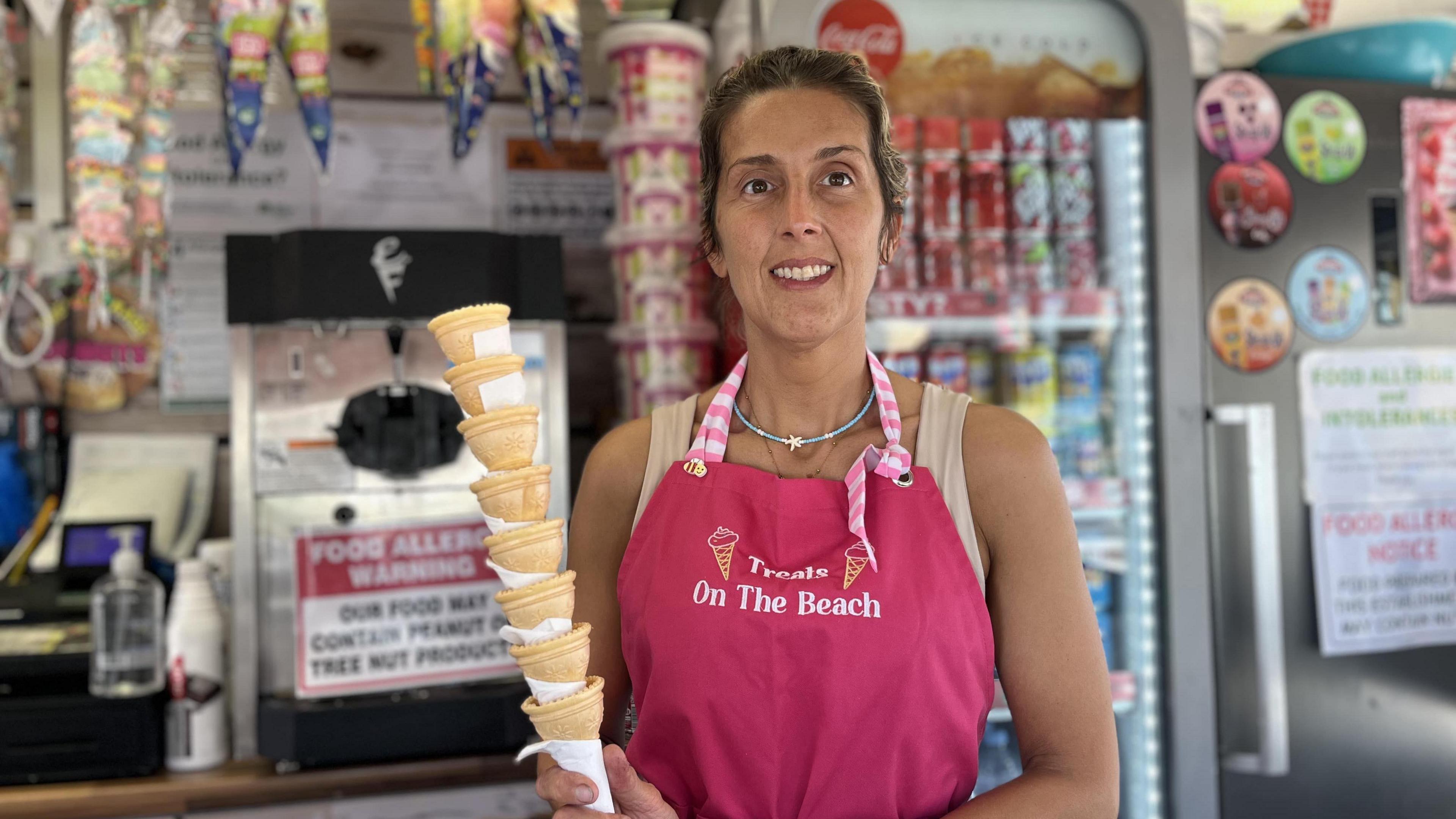 Close up image of Sadie Crick standing inside her food kiosk on Bognor seafront holding cones