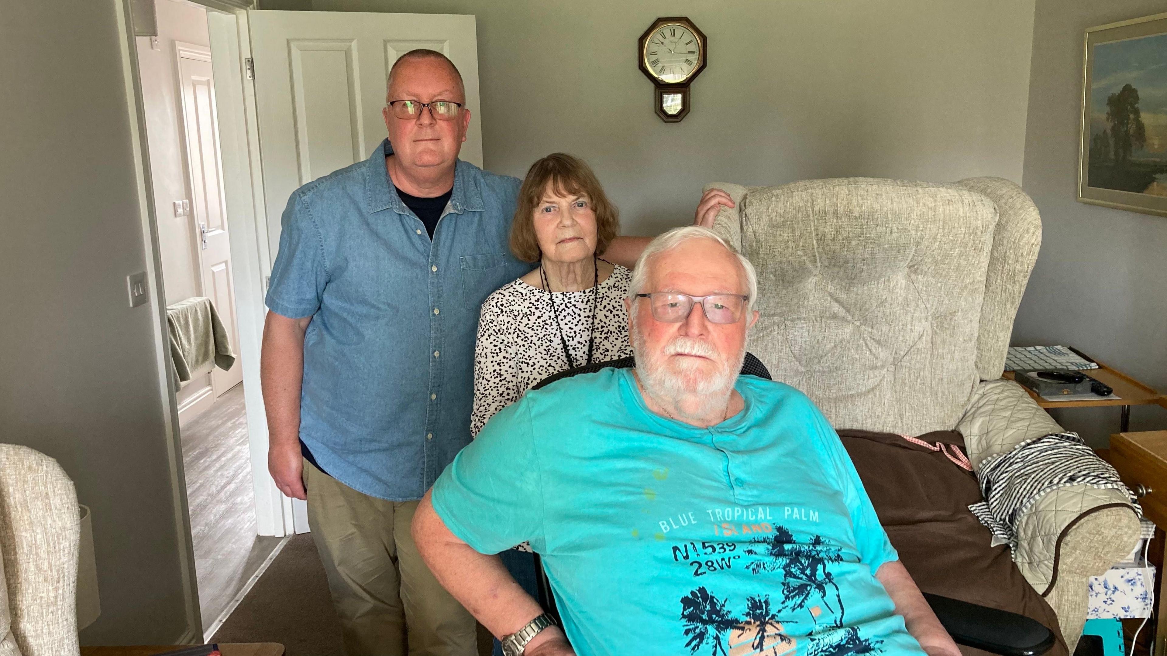 Stephen, Mary and Roger Ellis. They are in a living room.