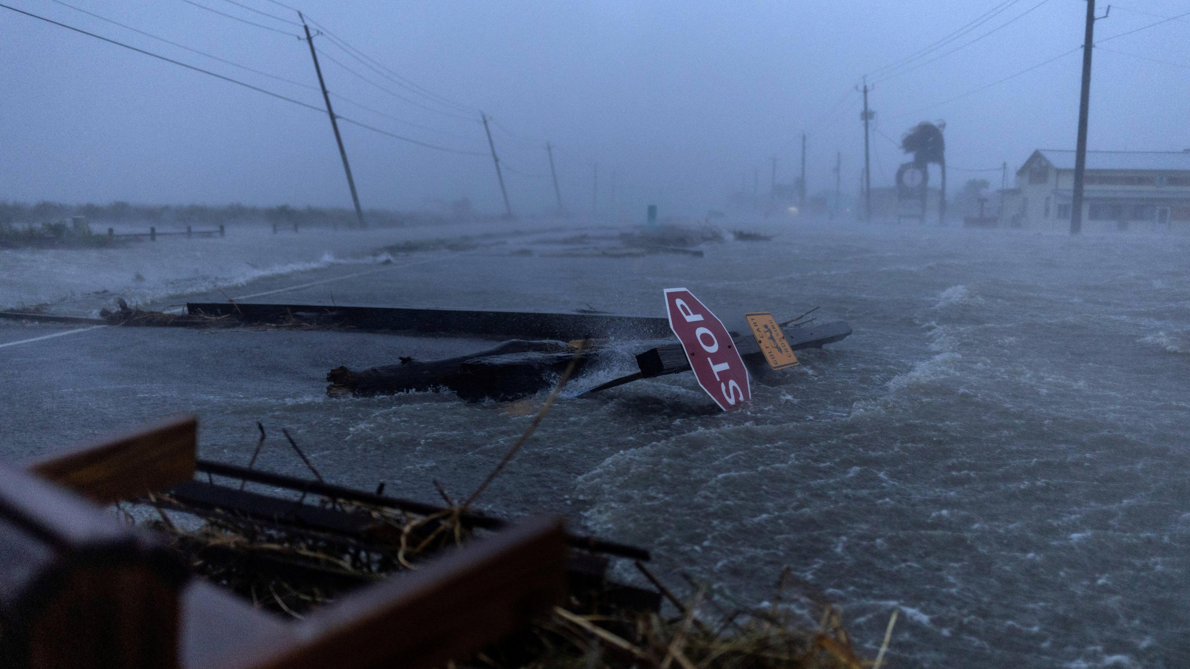 A flooded road is strewn with water and debris as strong winds blow