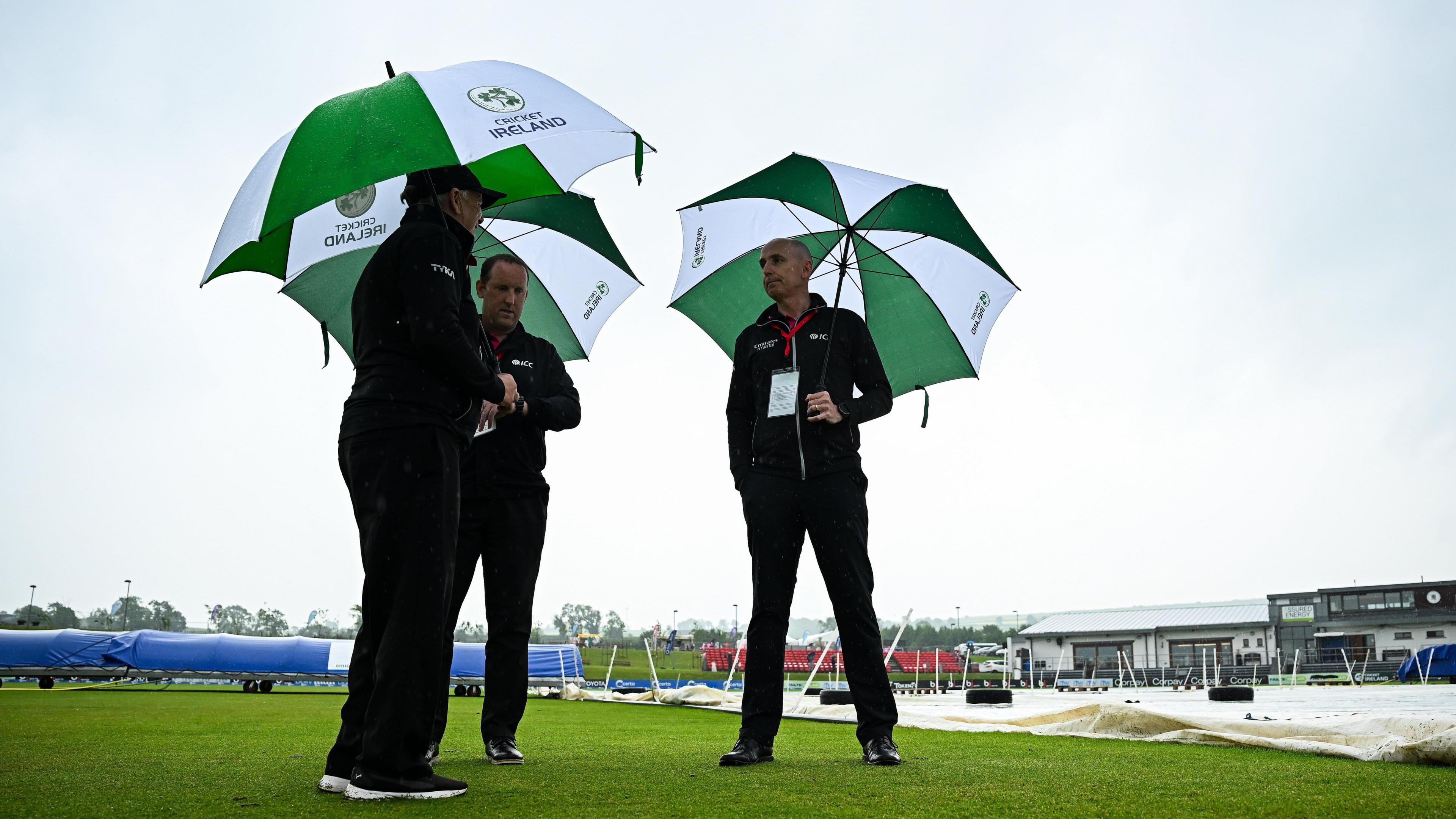 Umpires Mark Hawthorne, Aidan Seaver and Roly Black inspect the covers