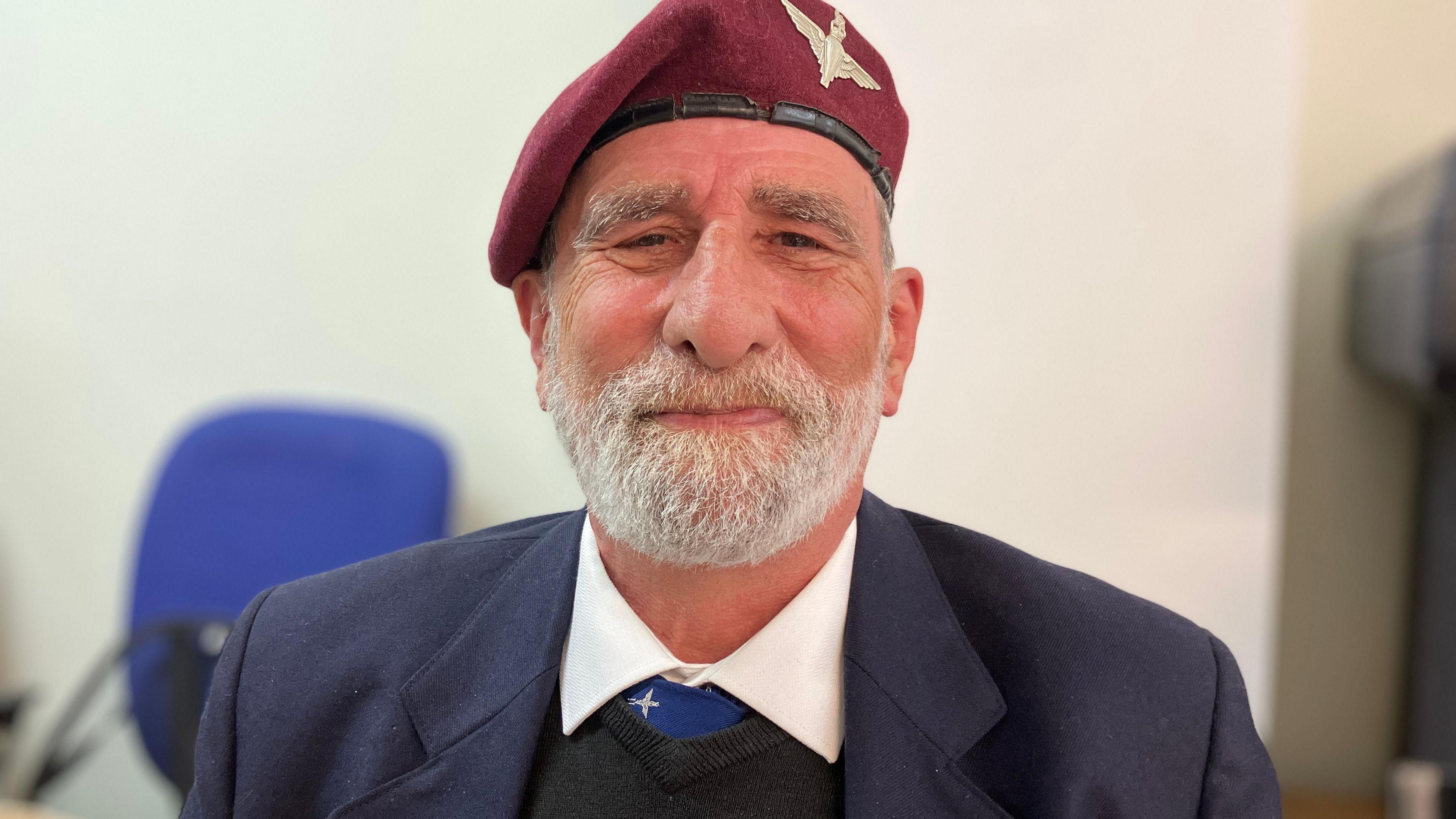 Mark Griffiths wearing a suit and red military beret. 