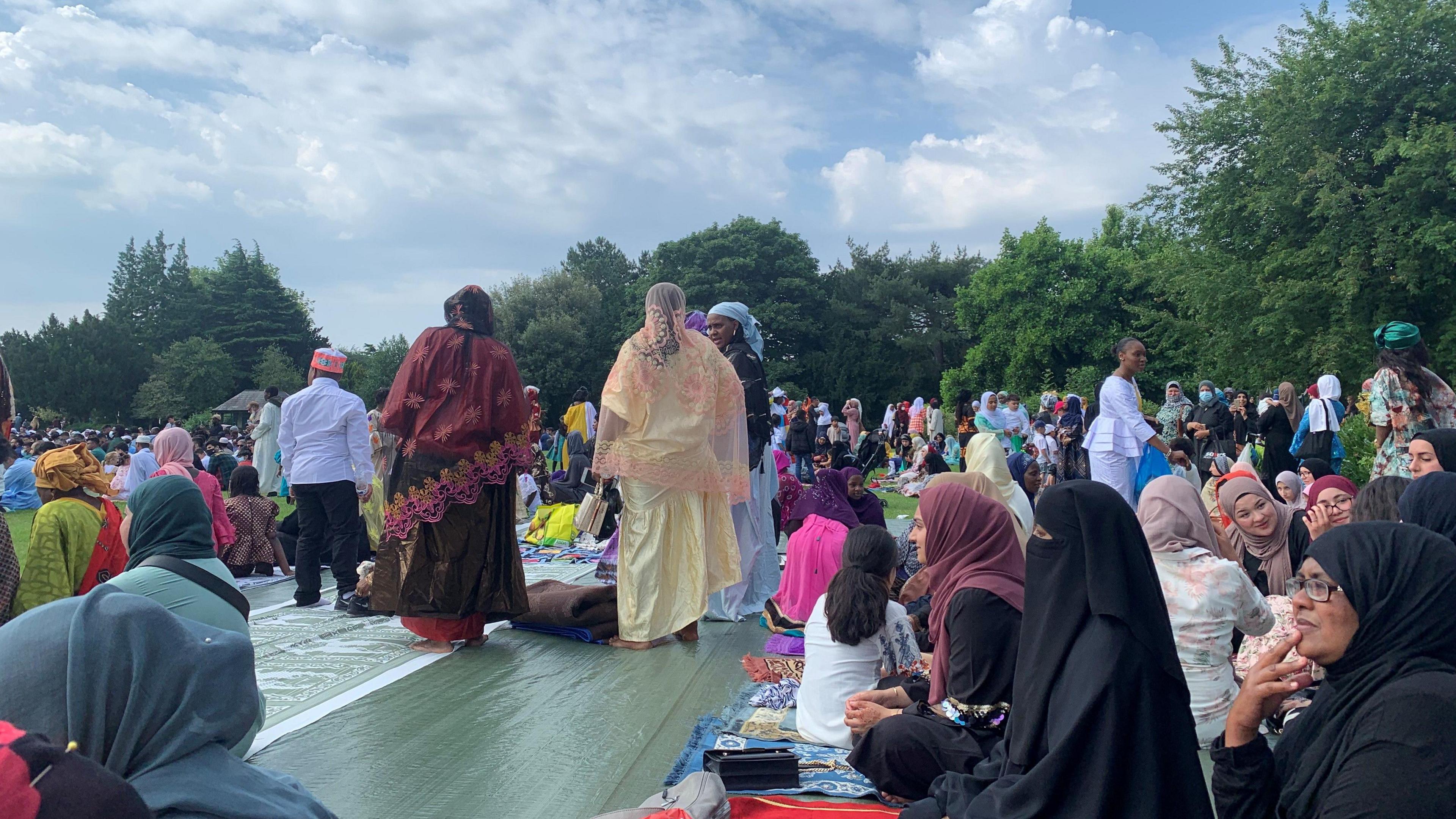 Muslim women dressed in their abayas and head scarfs sitting in preparation for eid prayers in the park