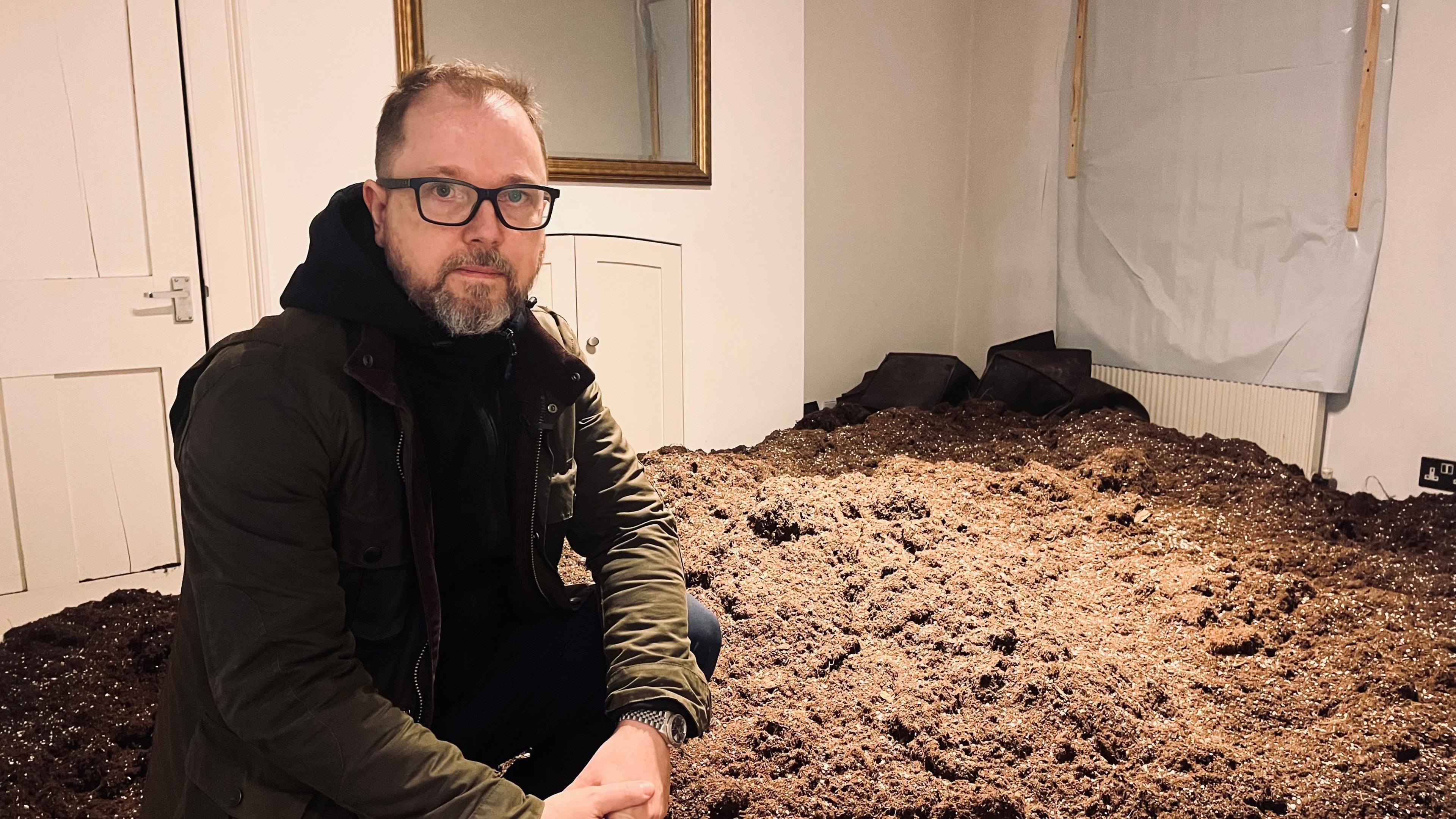 Charles Reeves surrounded by soil in his house