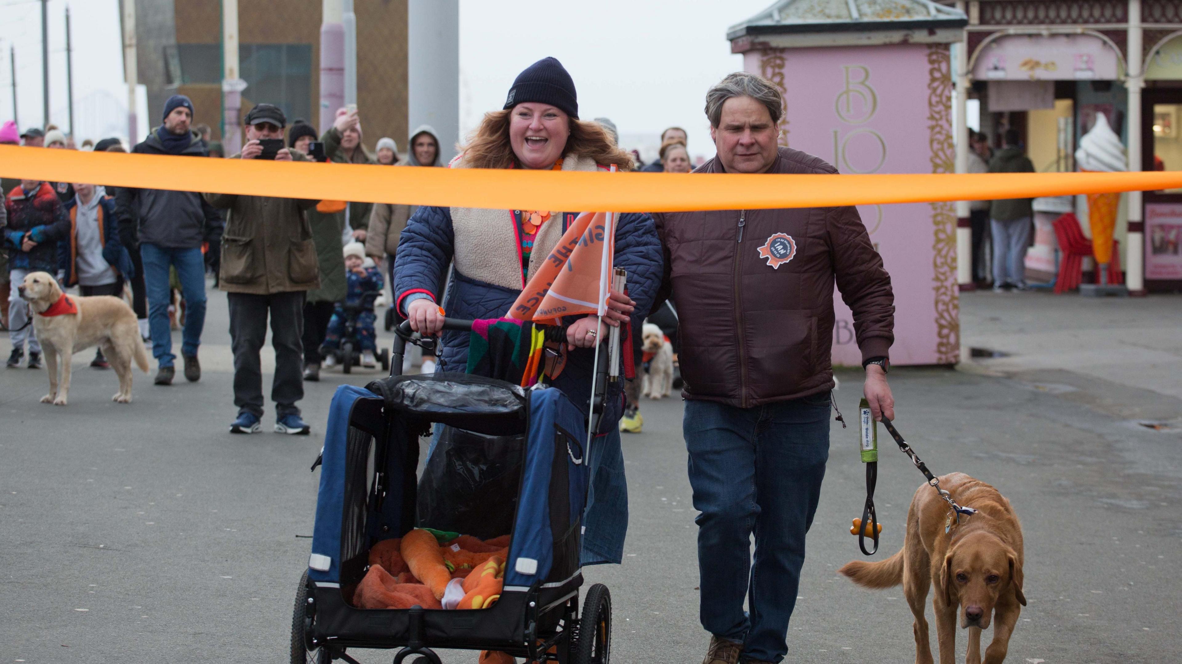 Gemma Fairhurst smiles as Mark Fielding walks his guide dog Ian to the finishing line of the charity walk on Blackpool Promenade.