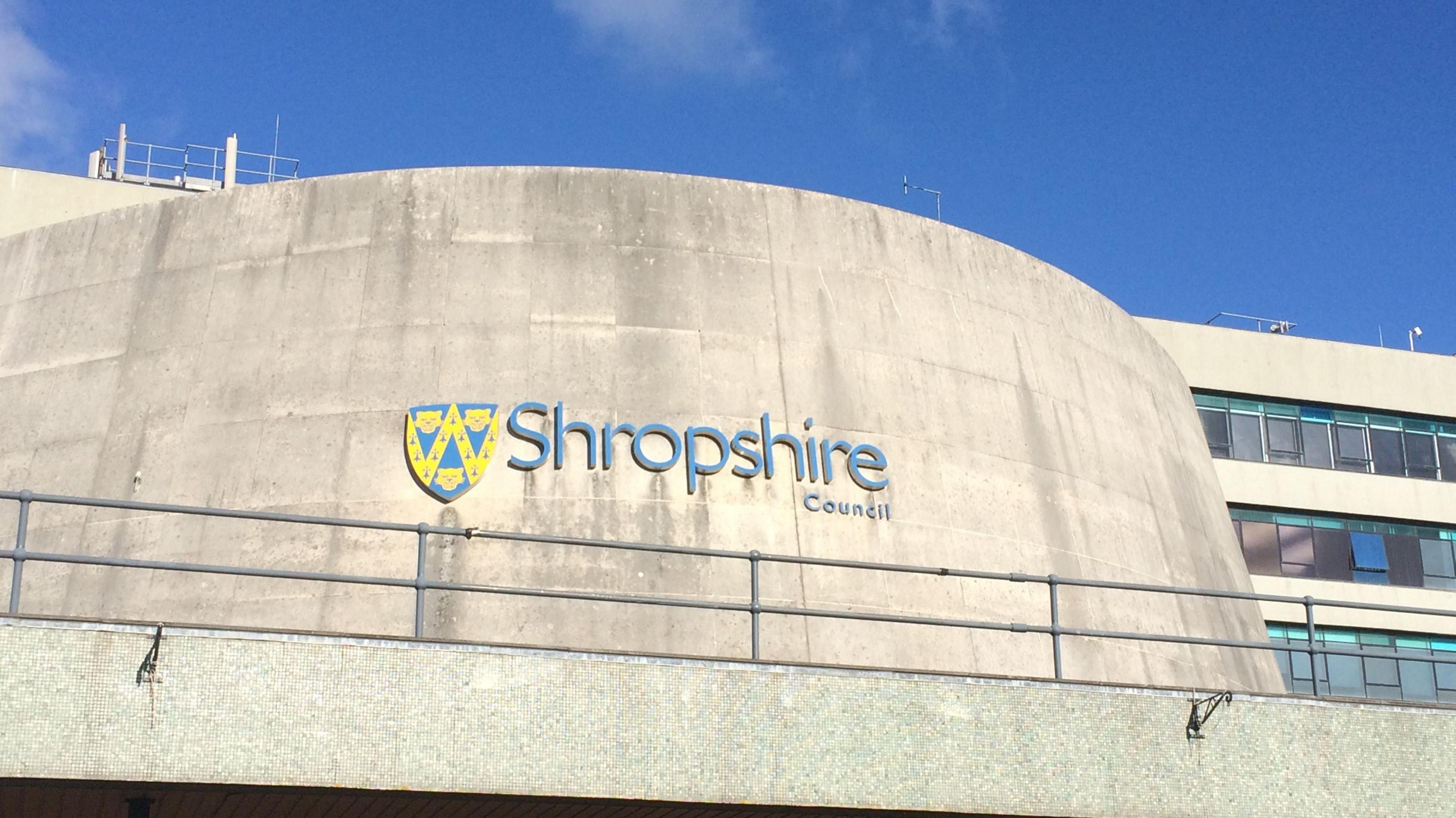 The curved concrete front of a large building with the words Shropshire Council in blue lettering