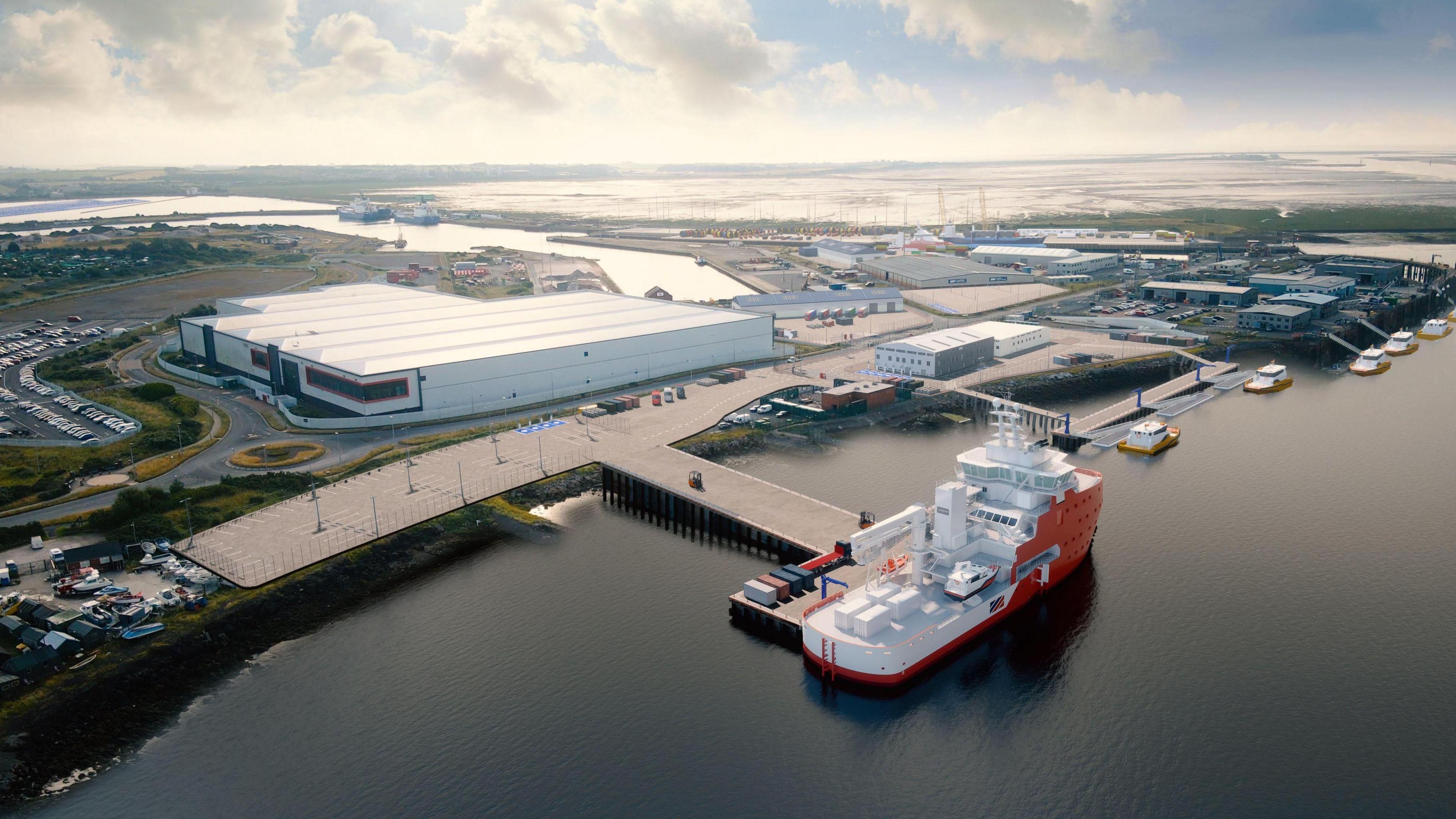 An aerial view of BAE systems in Barrow, Cumbria. In the forefront of the photo a large ship is moored on a dock with several smaller ships behind. On land there is a vast white building with many other building behind and a river course leads to Cavendish dock 