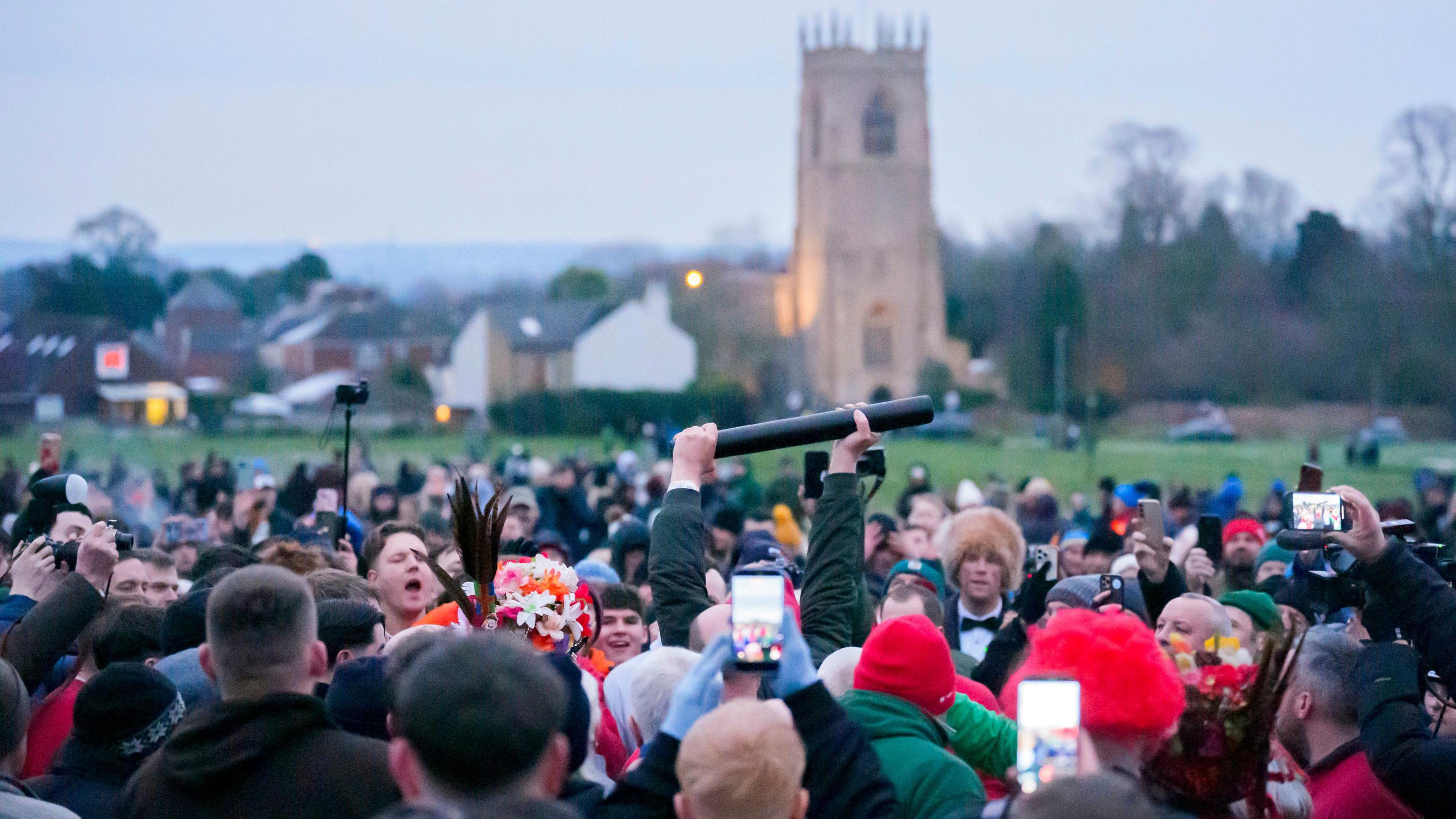 a person holding up a tube surrounded by lots of other people.