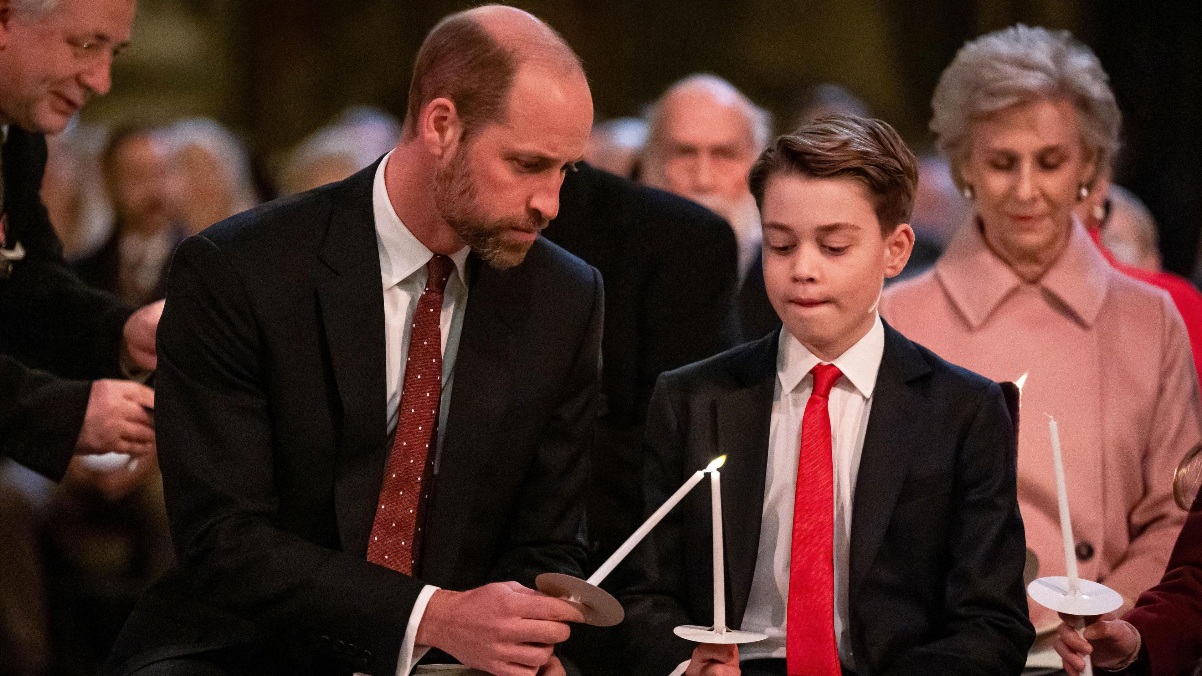 The Prince of Wales helps his son Prince George light a candle during the Together At Christmas carol service at Westminster Abbey