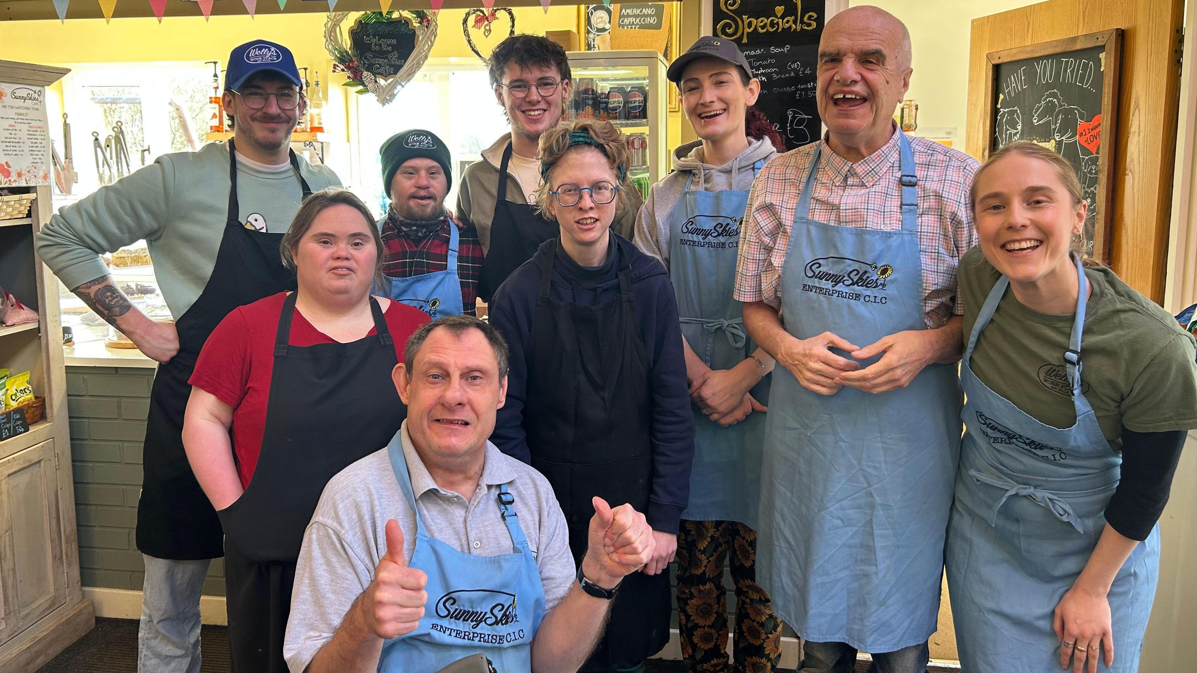 A group shot of people in the cafe wearing aprons