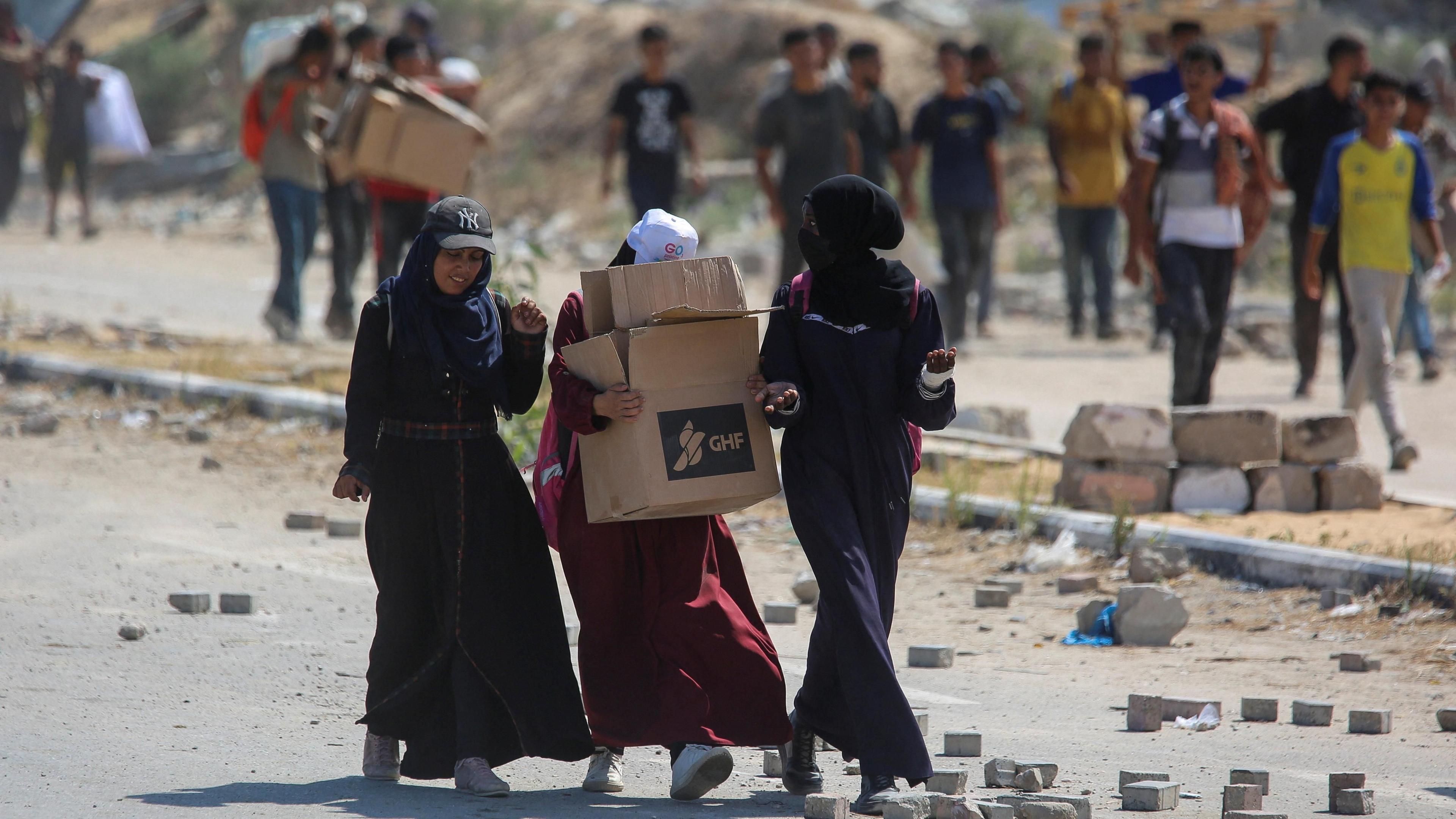 A Palestinian woman carries a box of food aid from the US-backed Gaza Humanitarian Foundation (GHF) in the central Gaza Strip (4 August 2025)