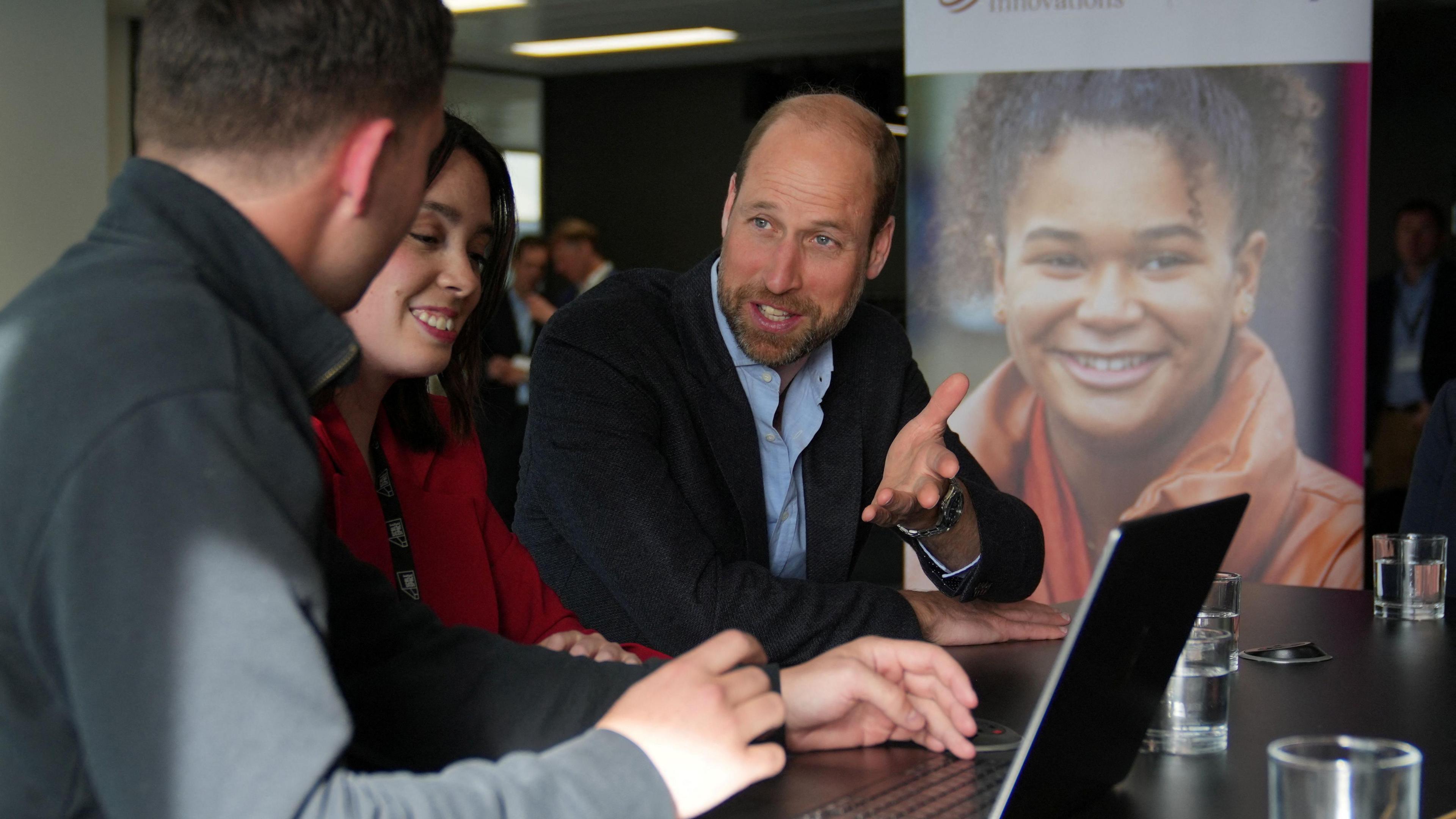 Prince William with volunteers of a mental health charity in London looking at a laptop computer