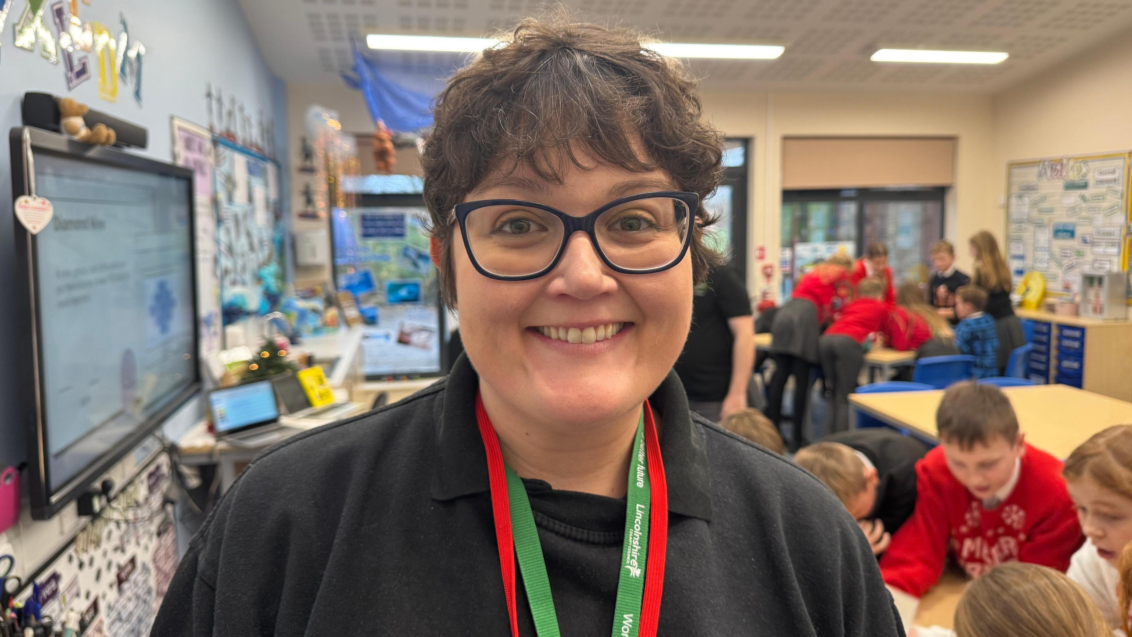 Woman smiling at the camera, wearing lanyards in a classroom