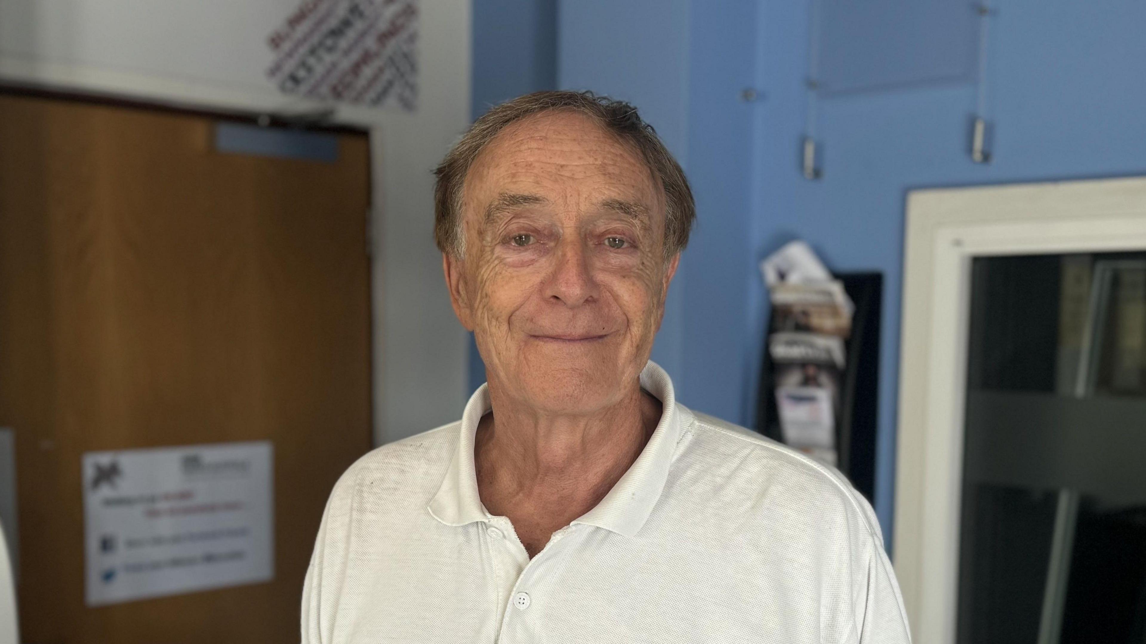 A man wearing a white polo shirt standing in the foyer of the BBC Radio Suffolk station building