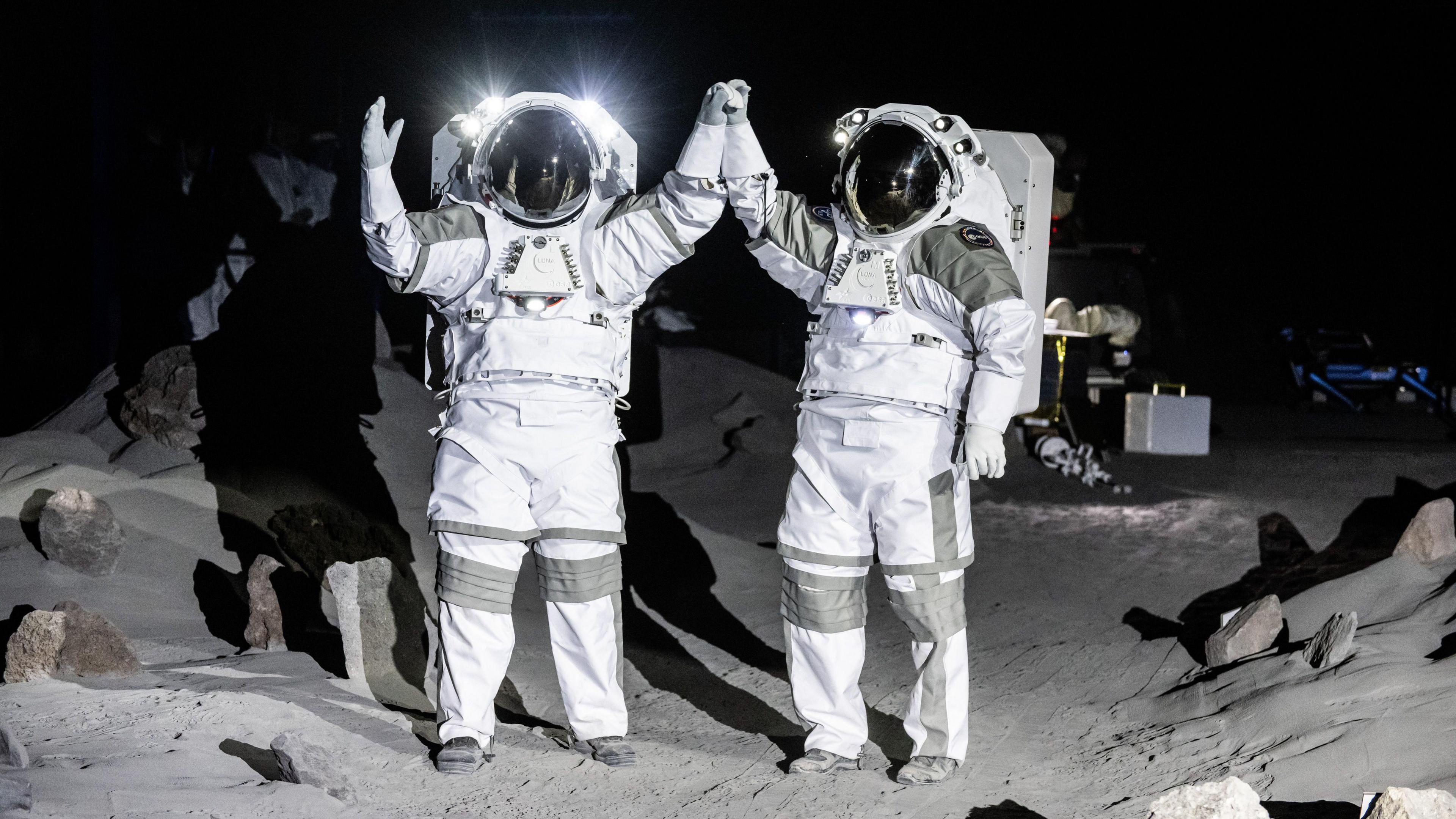 Two astronauts standing on the replica of the surface of the moon