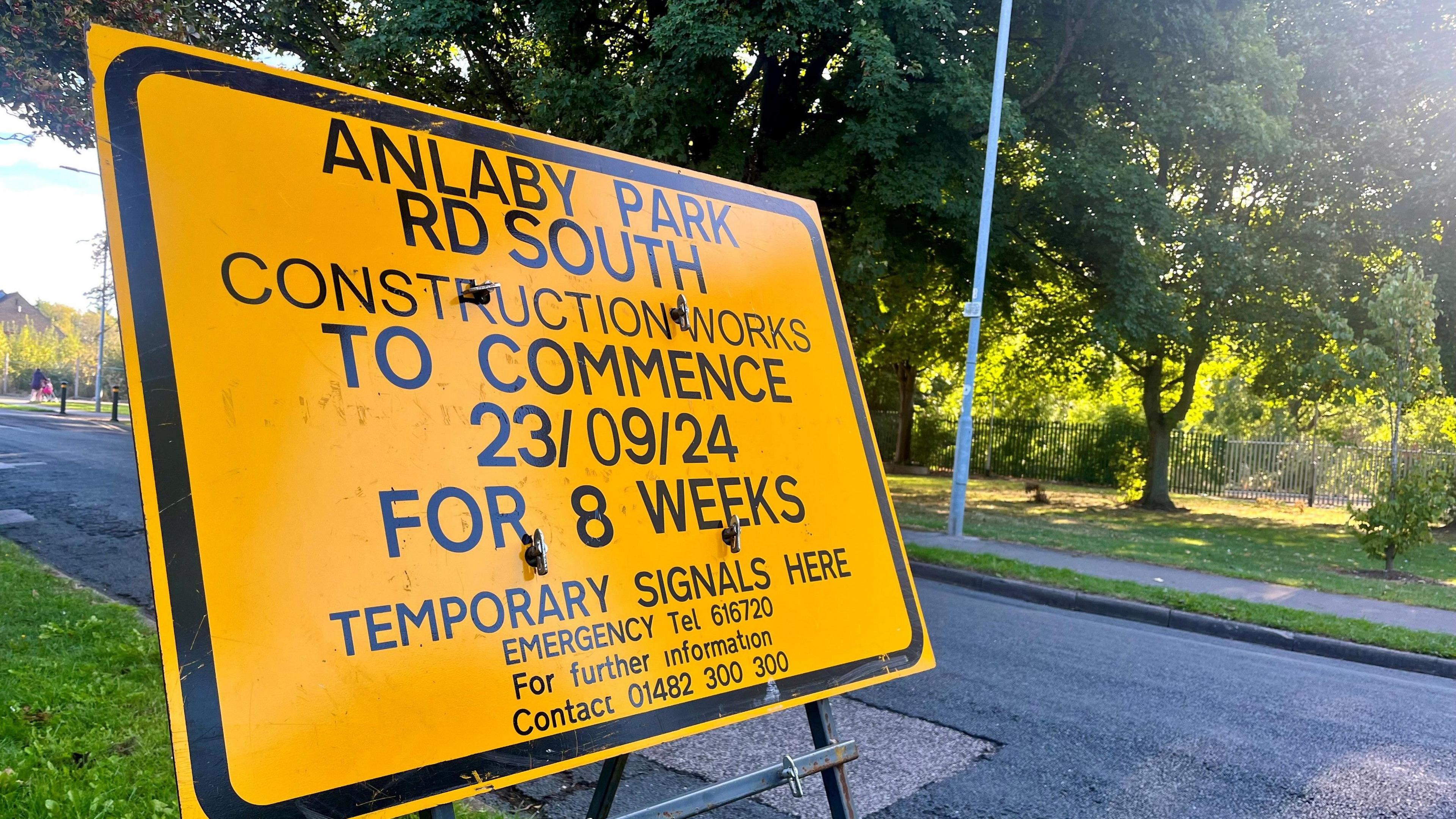 A yellow road sign on the grass beside the road stating there will be construction works on Anlaby Park Road South for eight weeks.