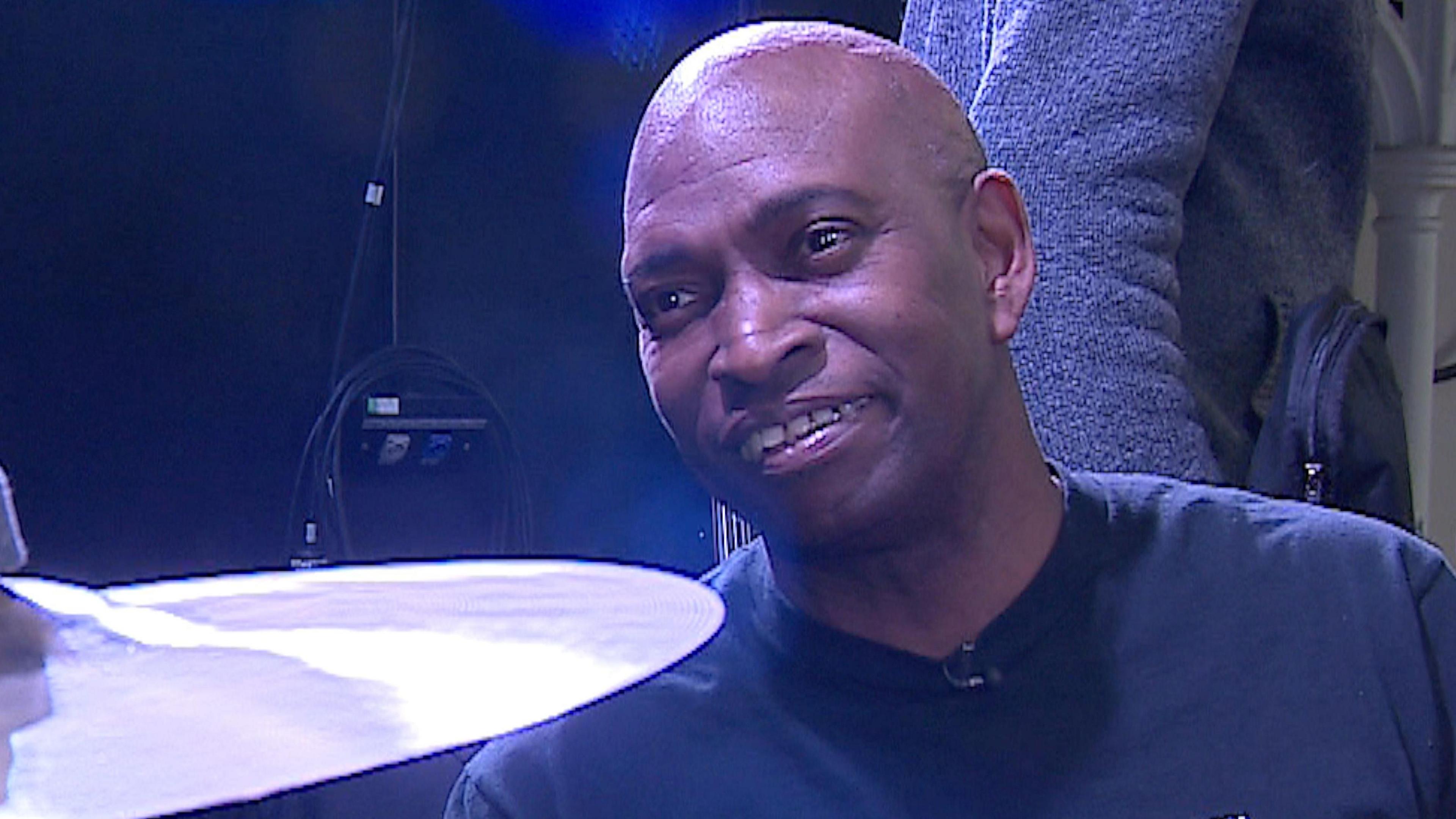 Winston Edwards with a cymbal from his drum set, wearing a navy T-shirt