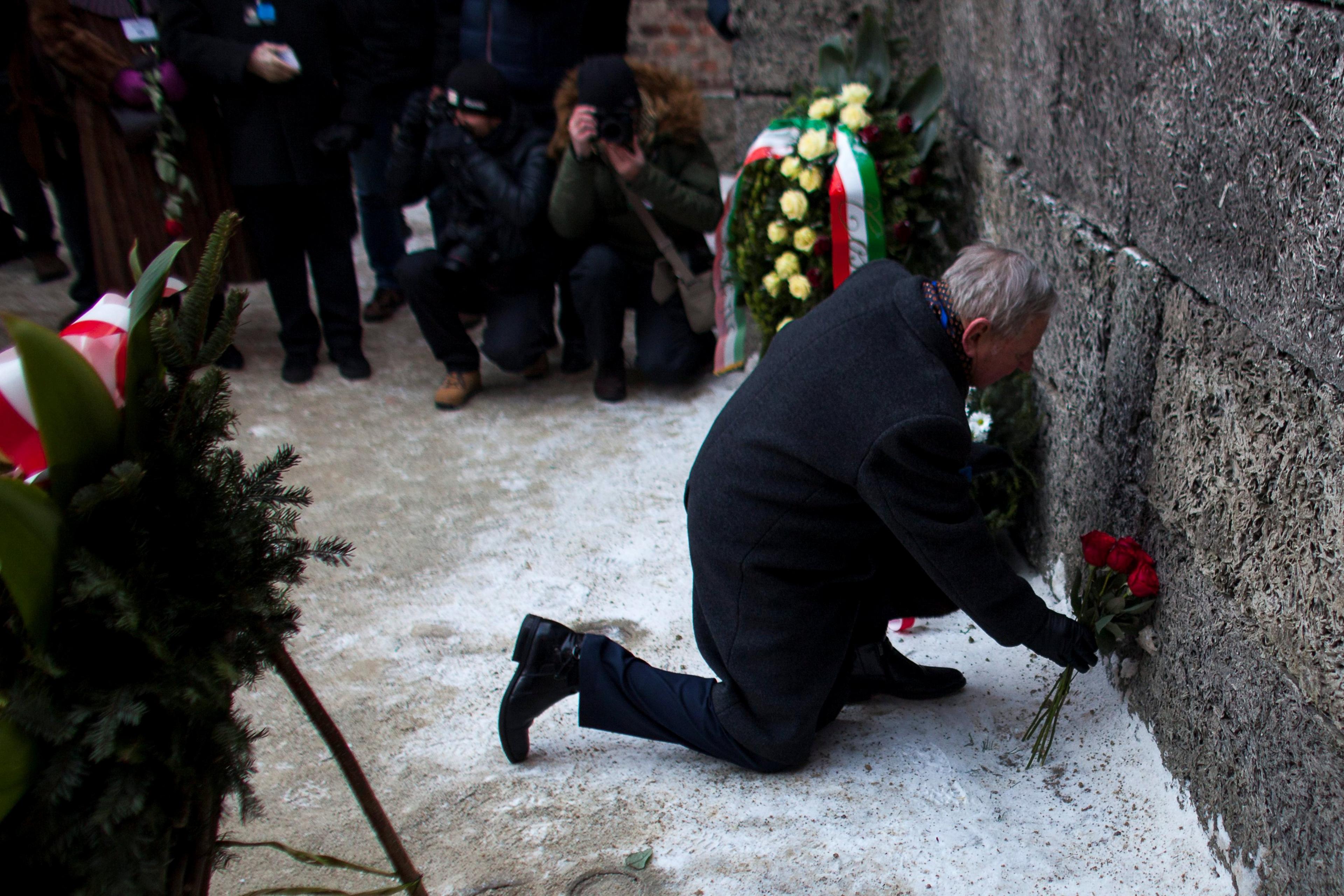 Survivor places flowers at the "death wall" in the former Nazi German concentration and extermination camp Auschwitz-Birkenau in Oswiecim, Poland