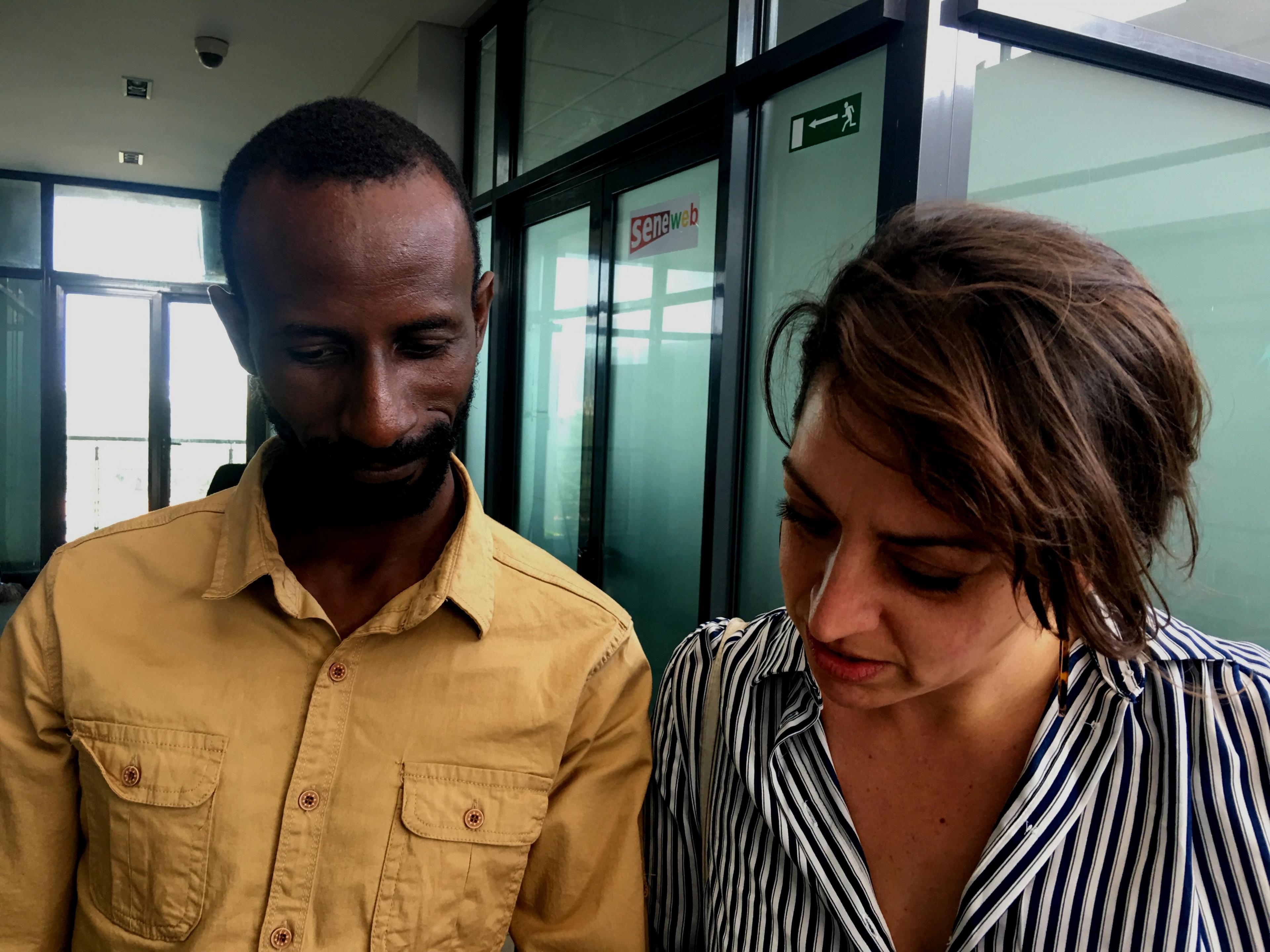 A man and a woman in an office look down at something together.