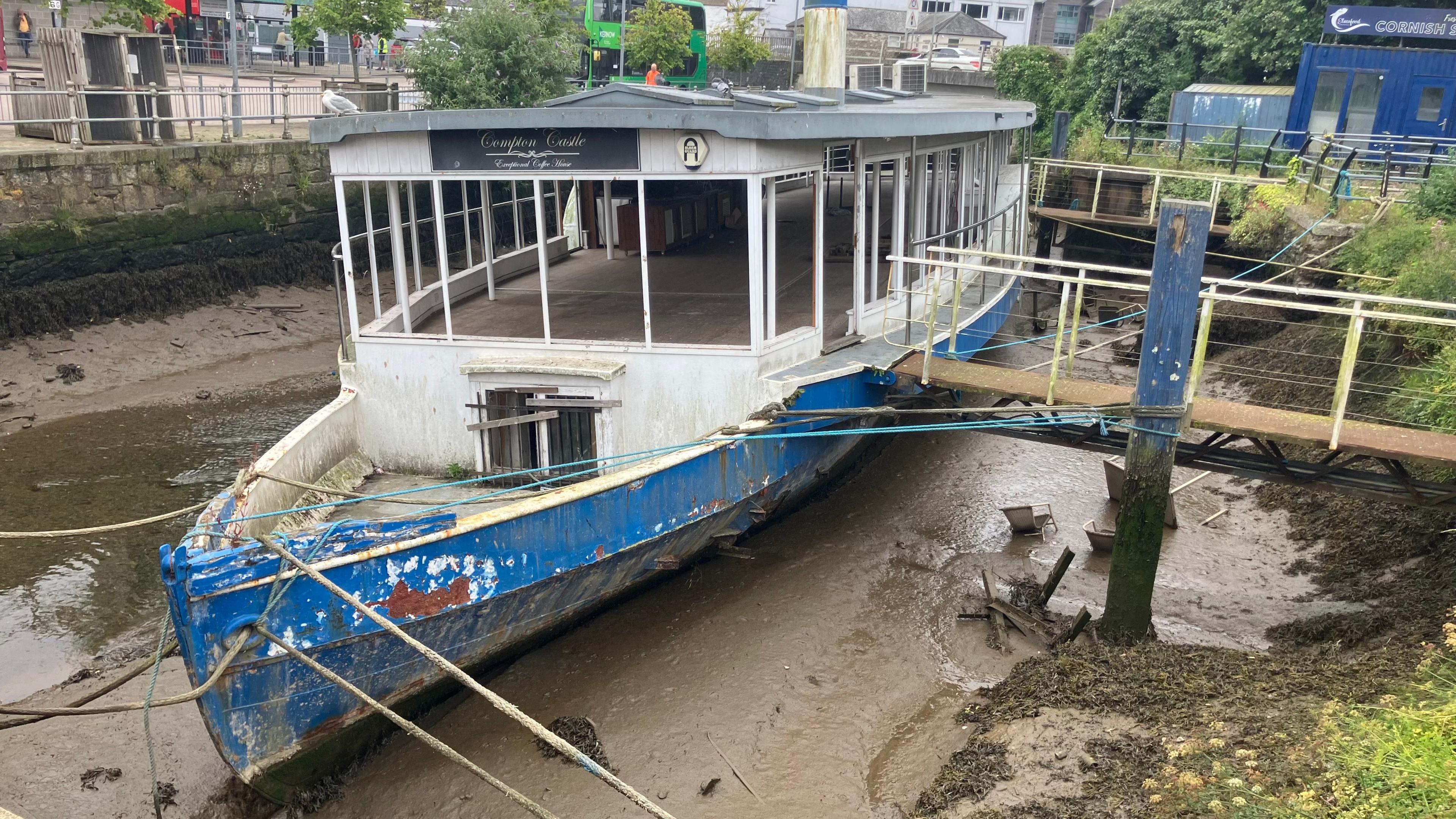 A derelict boat sits on the silt in. riverbed.