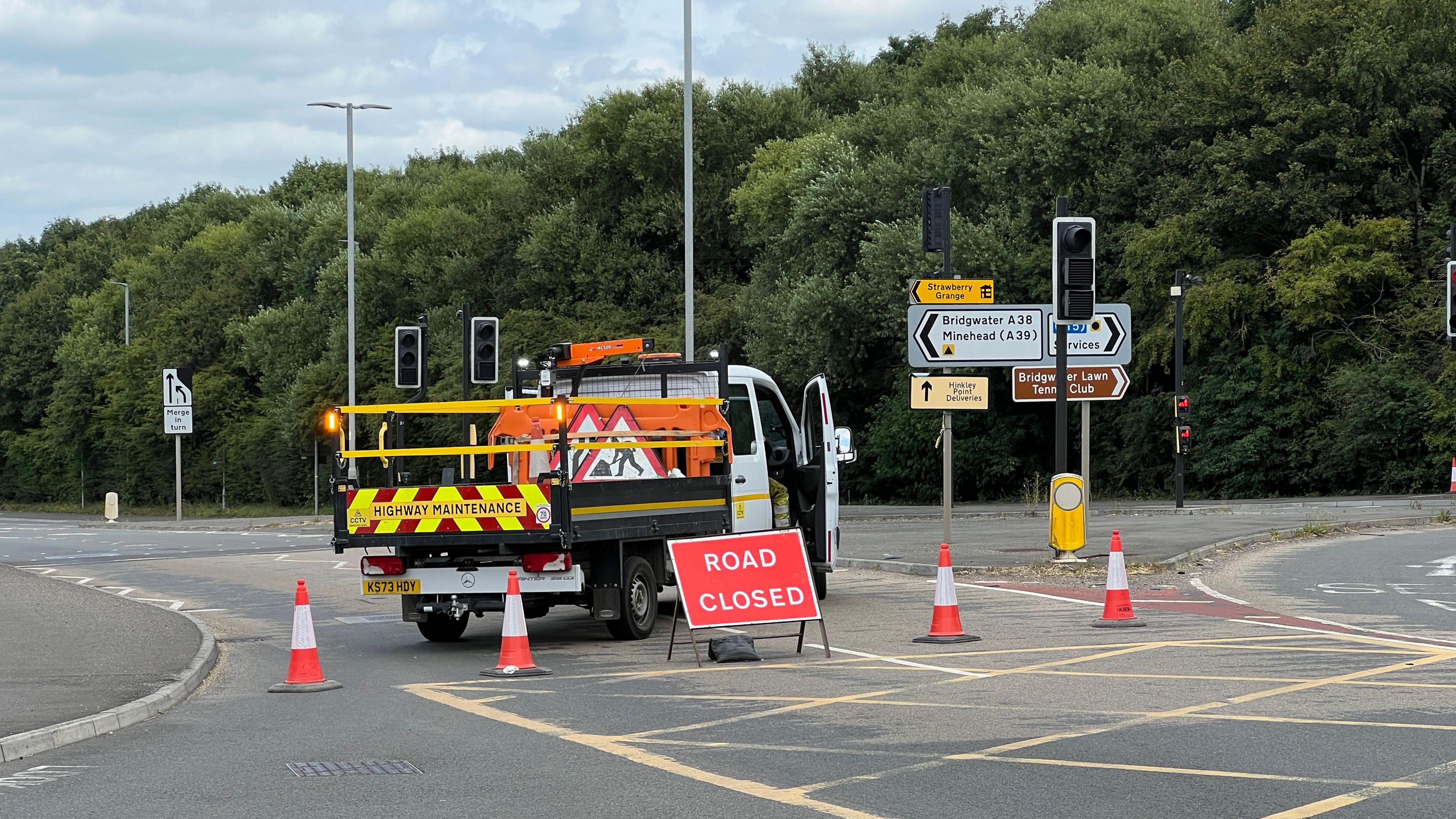 A38 Taunton Road in Bridgwater, Somerset. A highway maintenance van is parked across the road, blocking access to it. Cones and a road closed sign are also in the picture. 