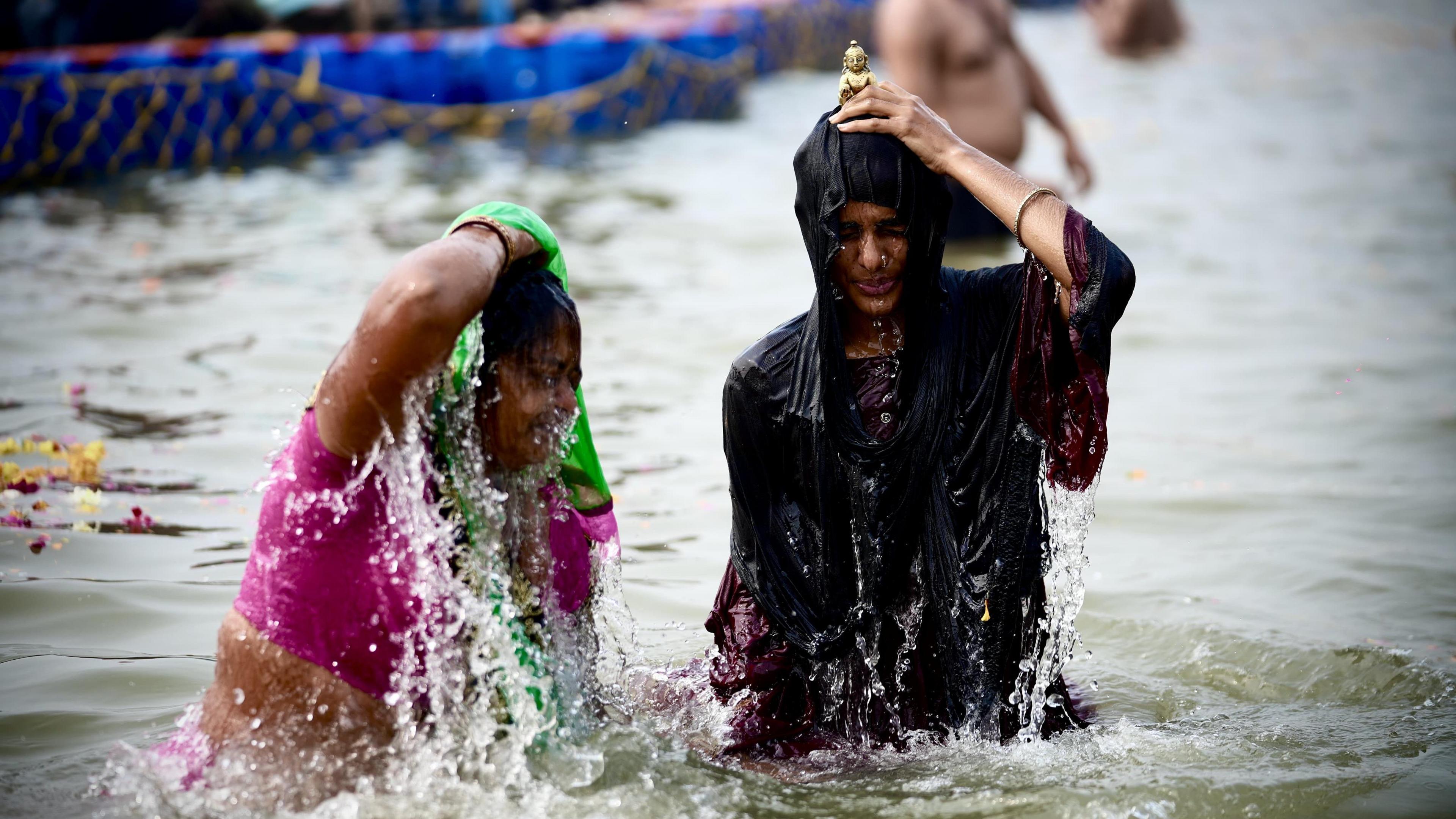 Two women take a dip in the river at the Kumbh Mela