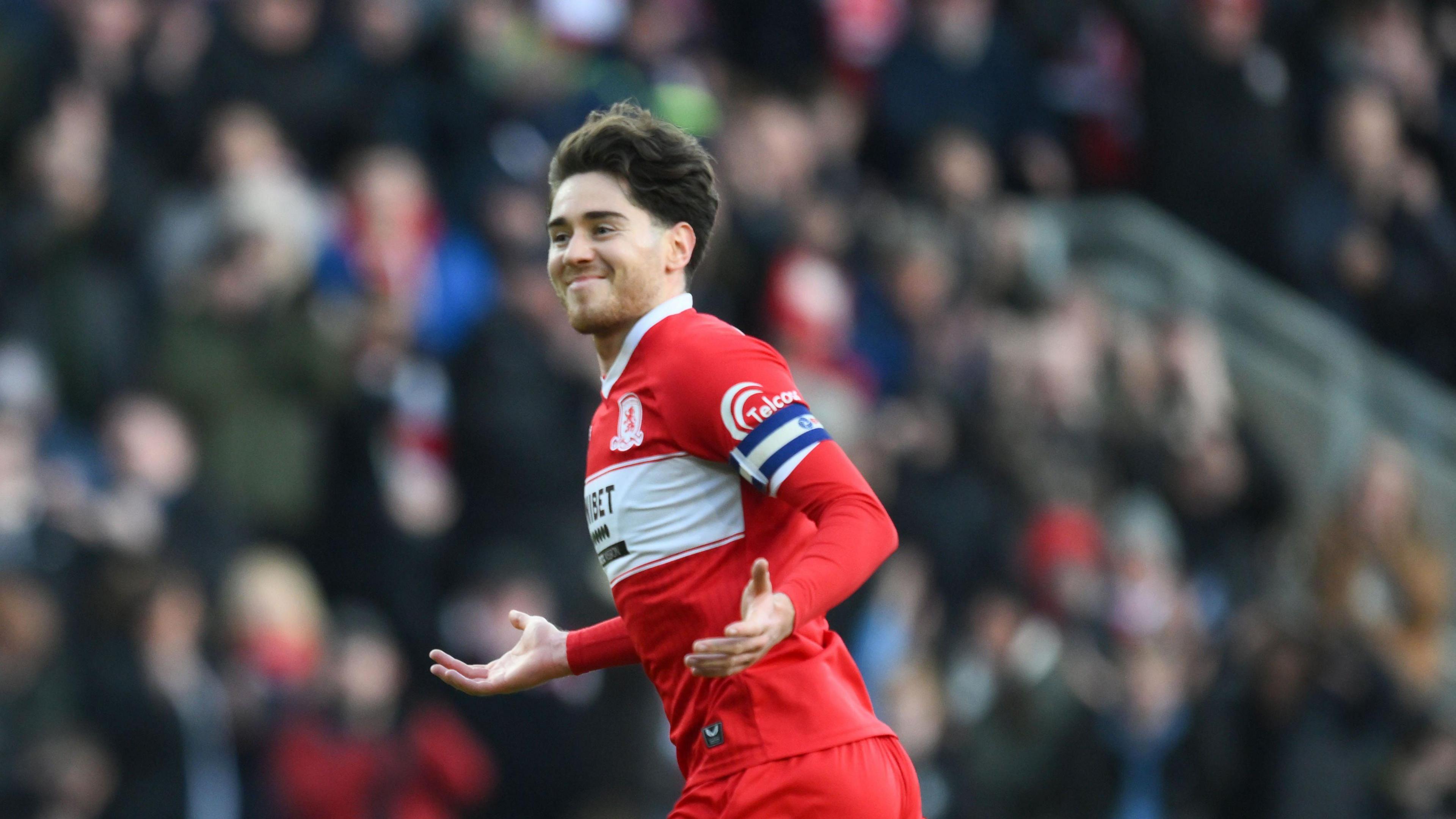 Middlesbrough player Hayden Hackney has a beaming smile and his arms out towards the fans after scoring a great goal