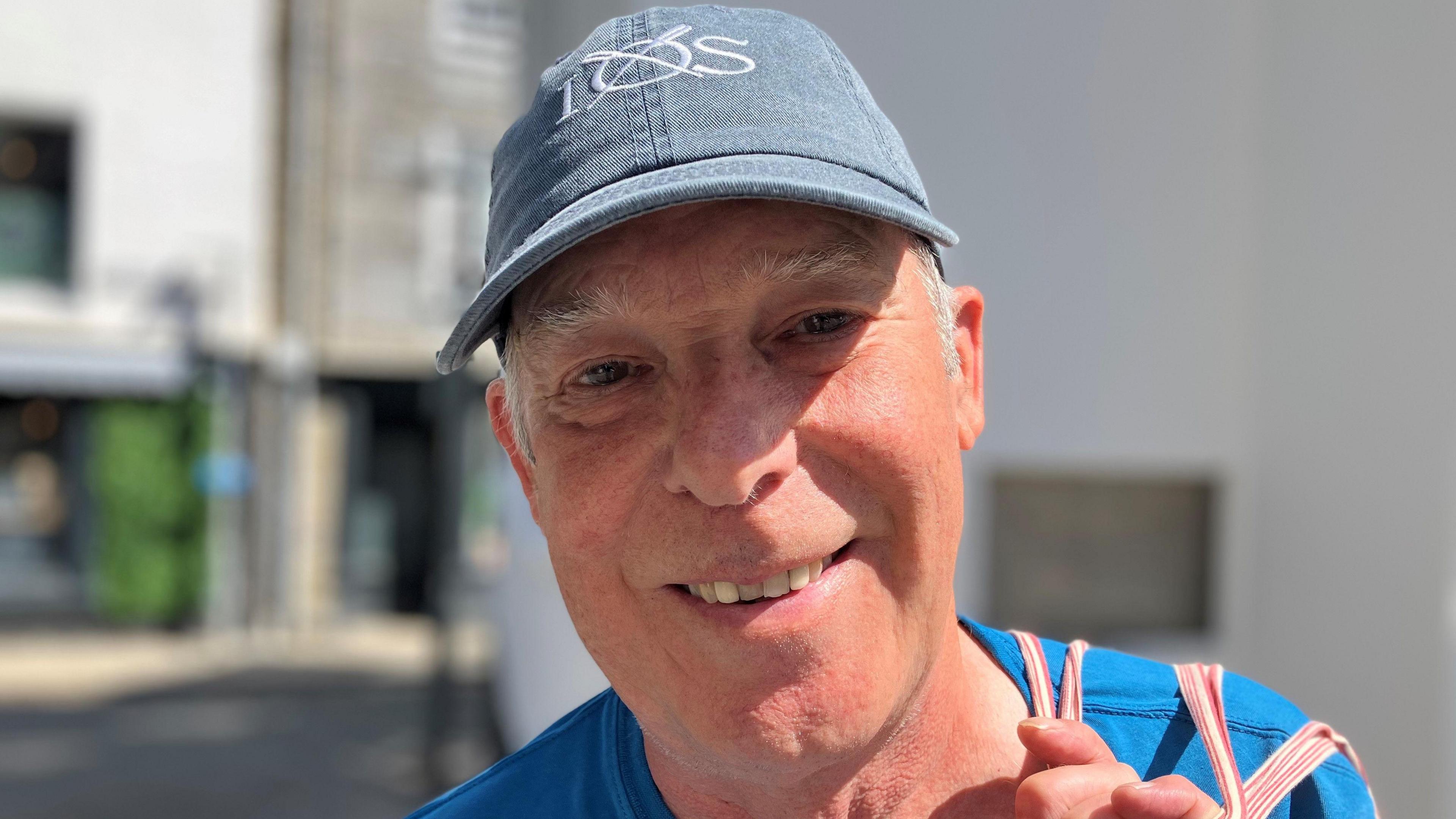 A man wearing a baseball cap and smiling at the camera