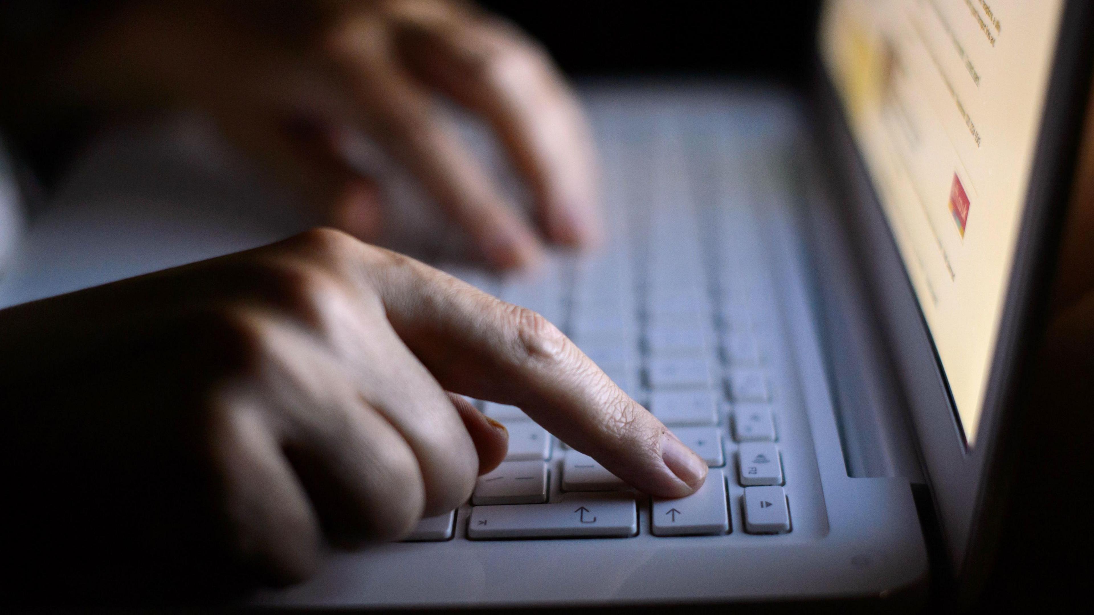 Person holding their fingers over a laptop keyboard.