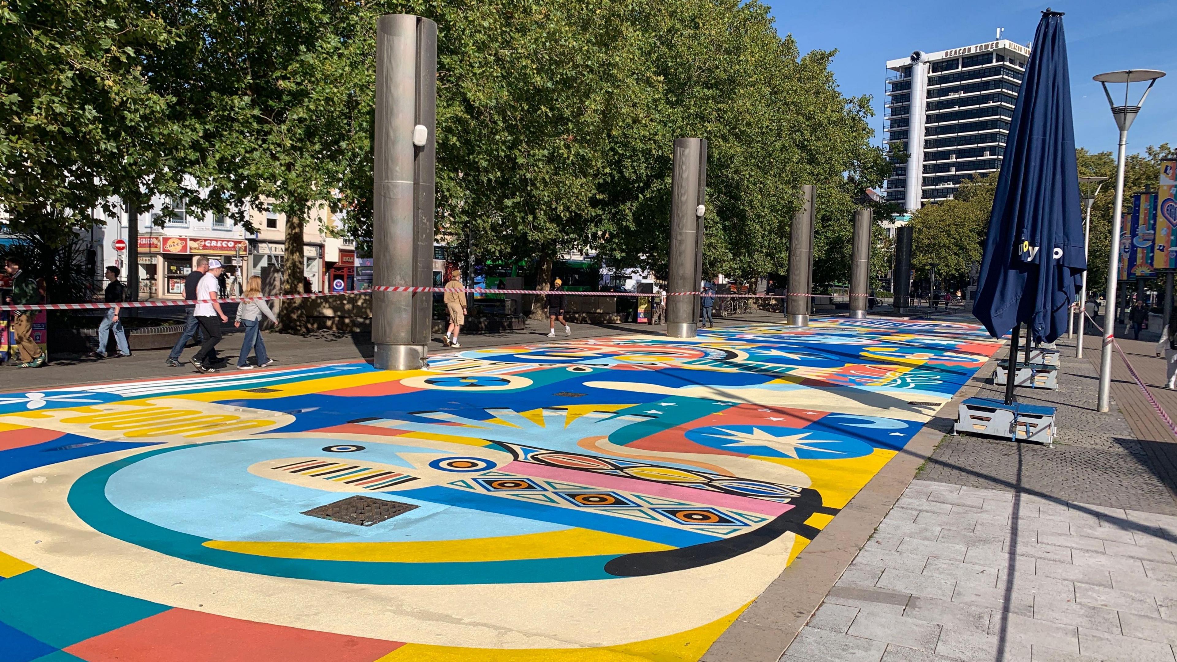 A long and large colourful mural has been painted into the gravel in Bristol's Centre Promenade. 