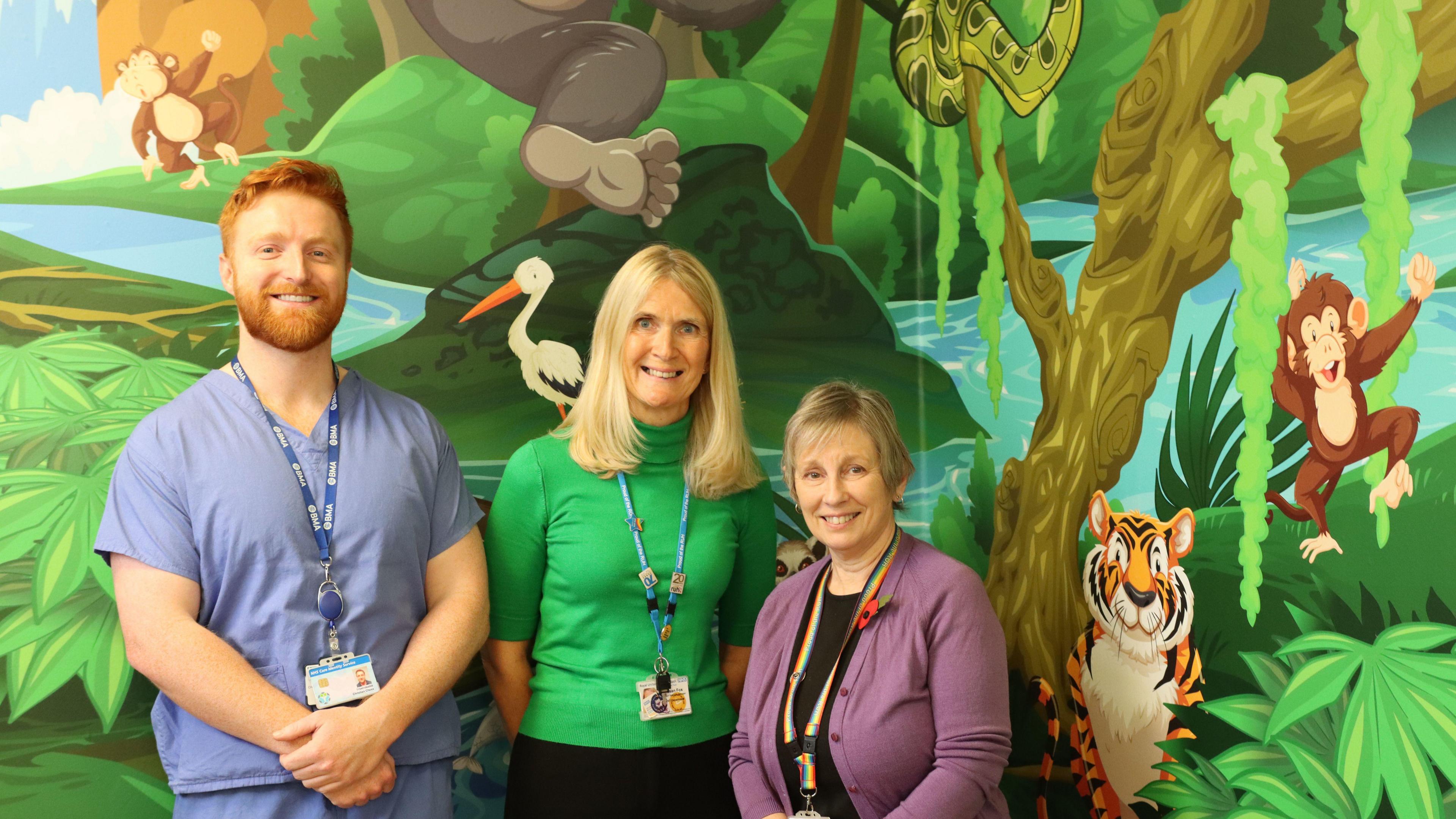 Staff from the Ear, Nose and Throat department beside a new cartoon-style jungle scene on a wall.
