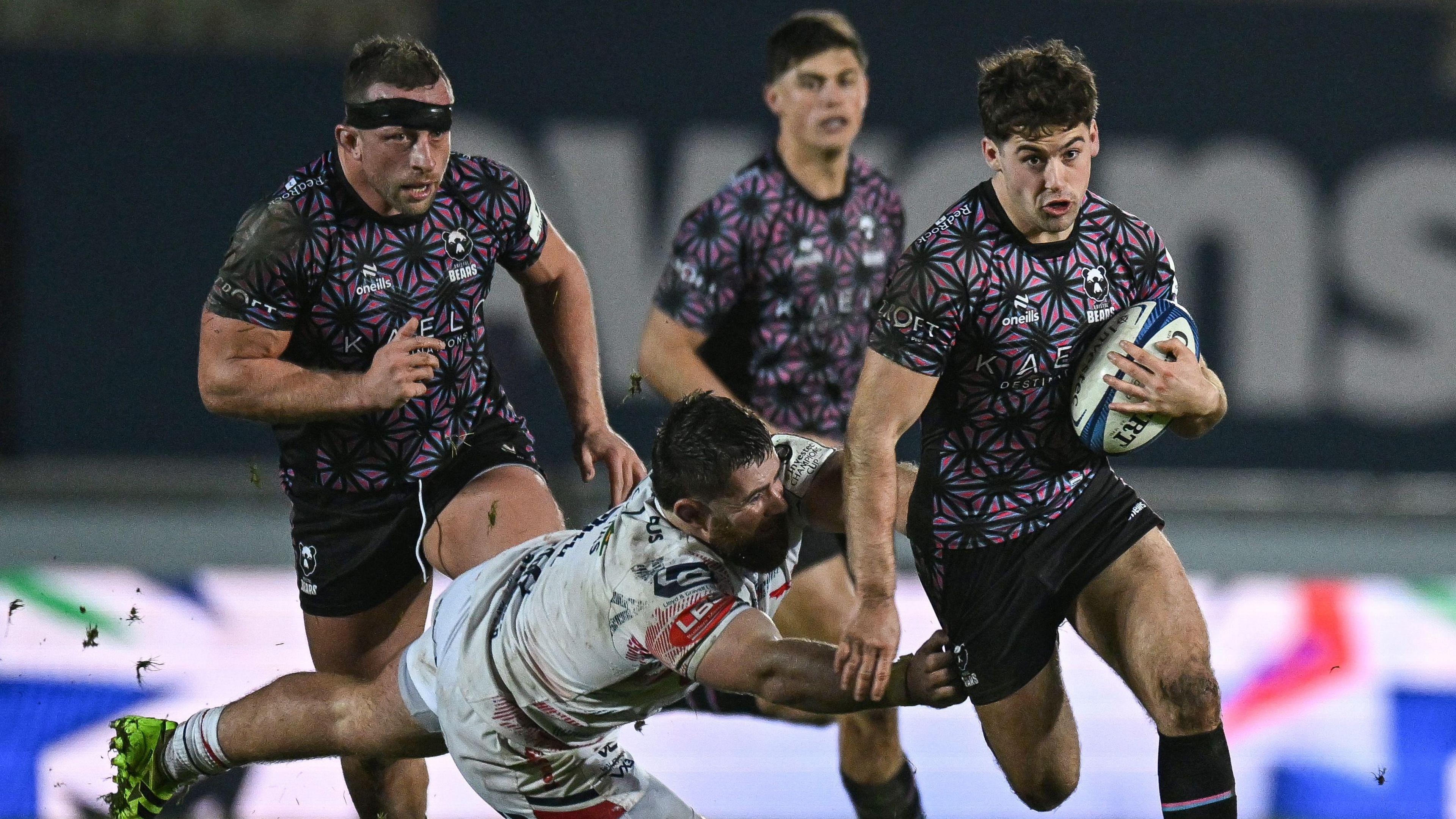 Sam Worsley (right) of Bristol Bears runs with the ball under his arm as he is almost tackled by a Scarlets player