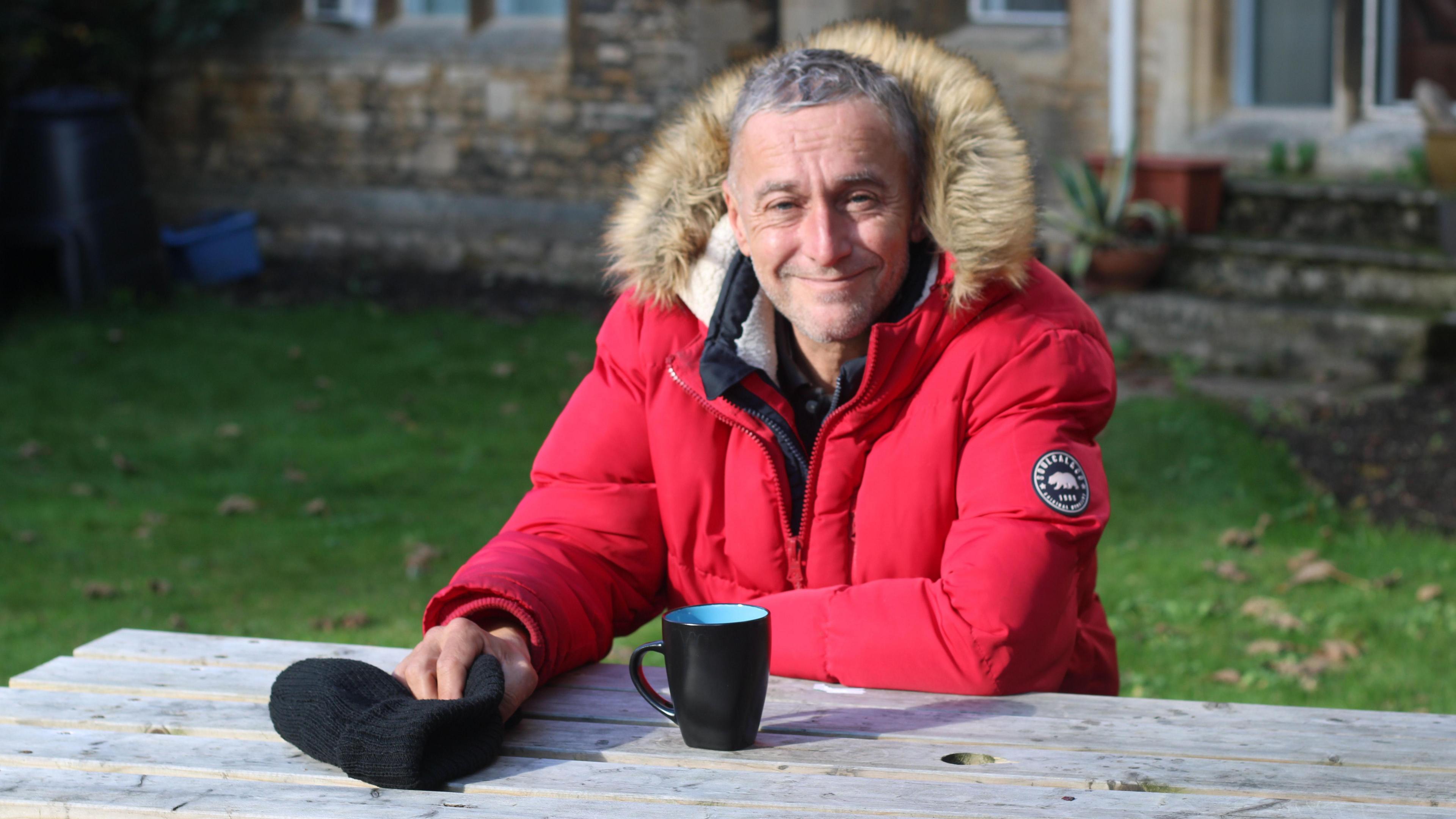 Nigel sitting on a bench smiling 