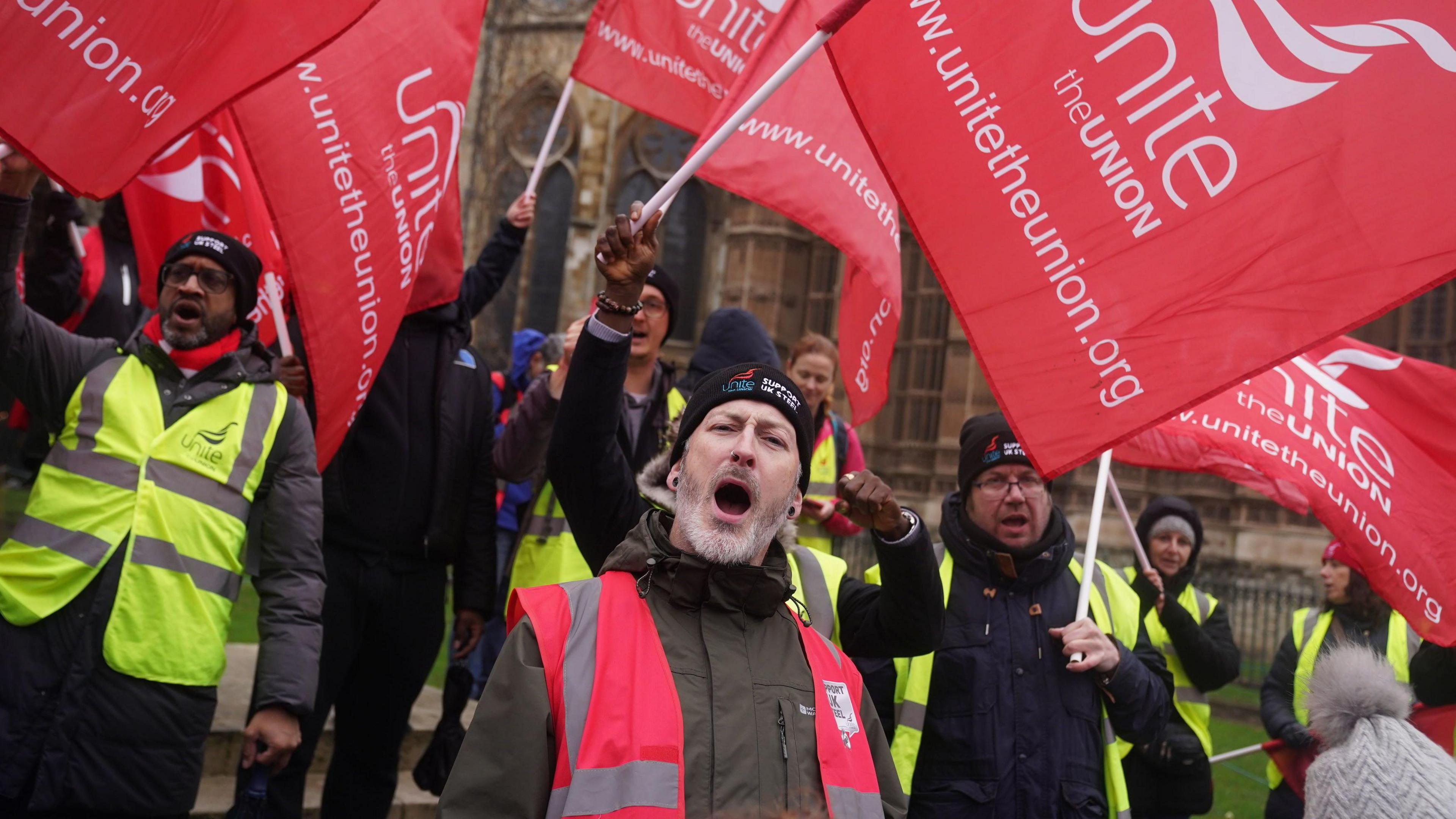 Steelworkers from Port Talbot holding Unite flags and shouting.