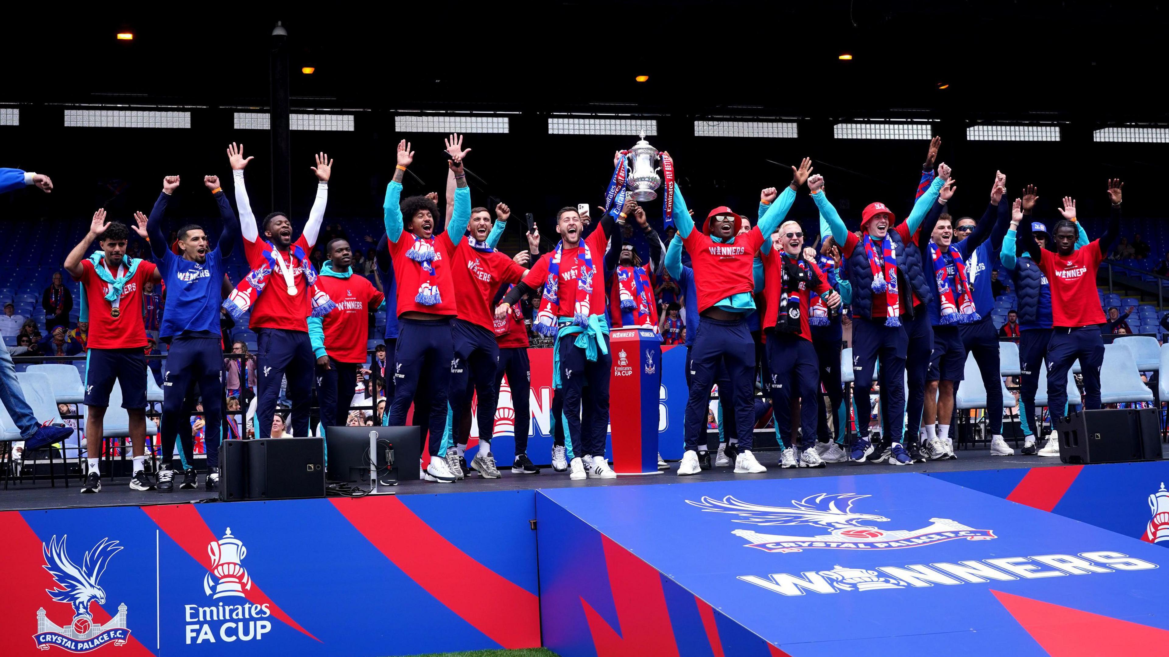 The team standing on stage lifting the FA Cup