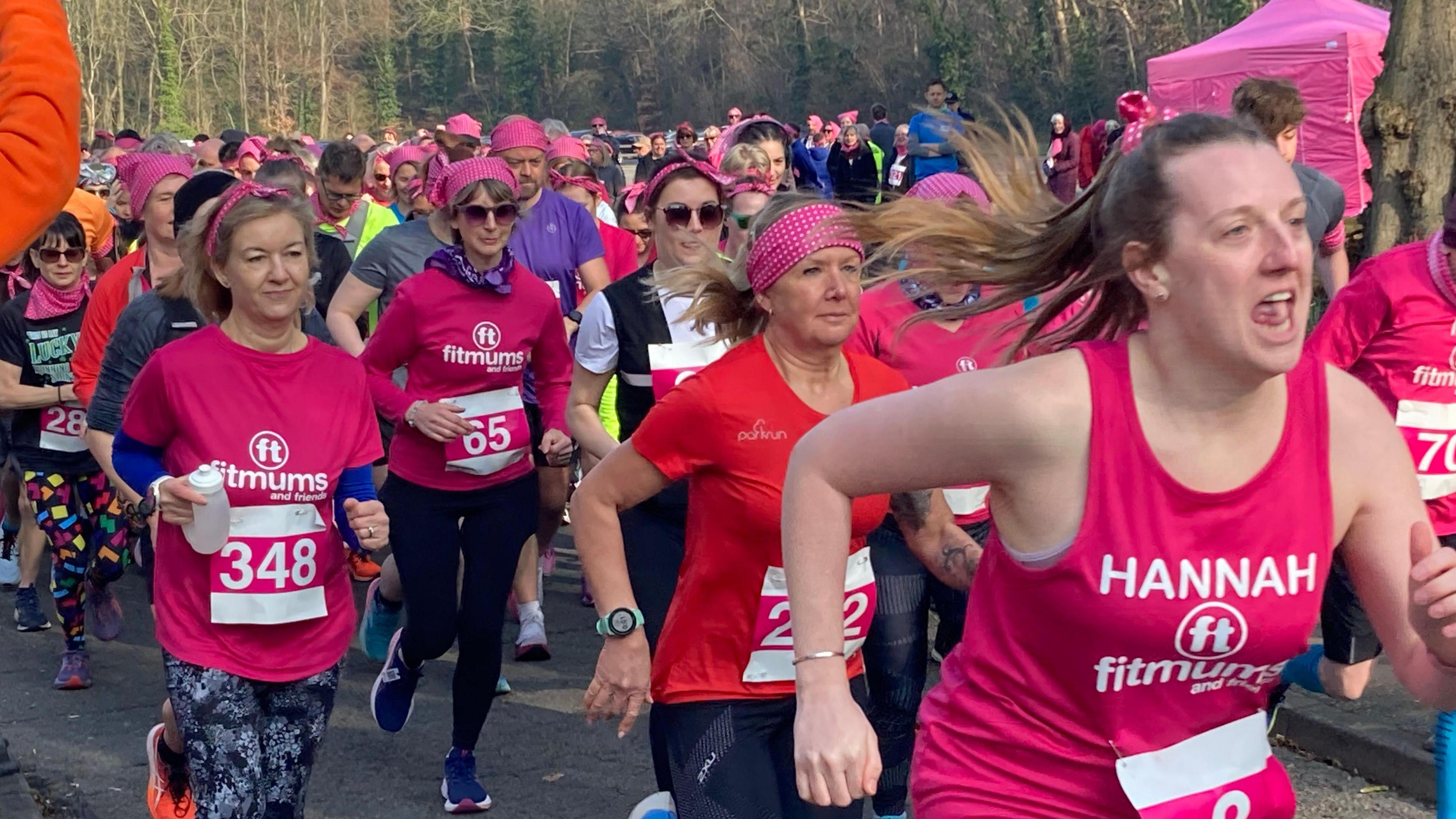 Dozens of runners, mainly women and many wearing pink, set off from the start line of a charity run.