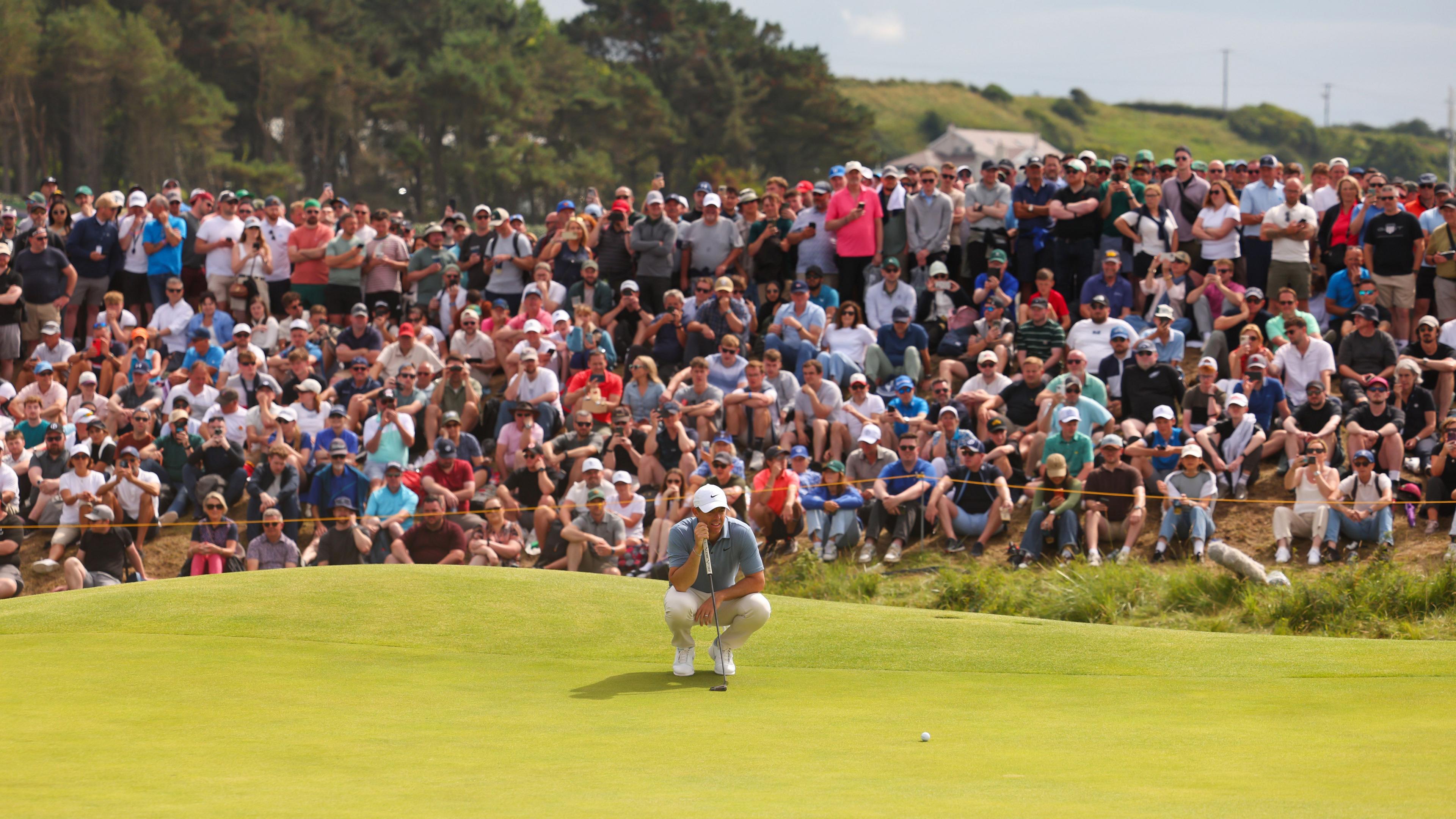Rory McIlroy lines up a put with hundreds of fans watching