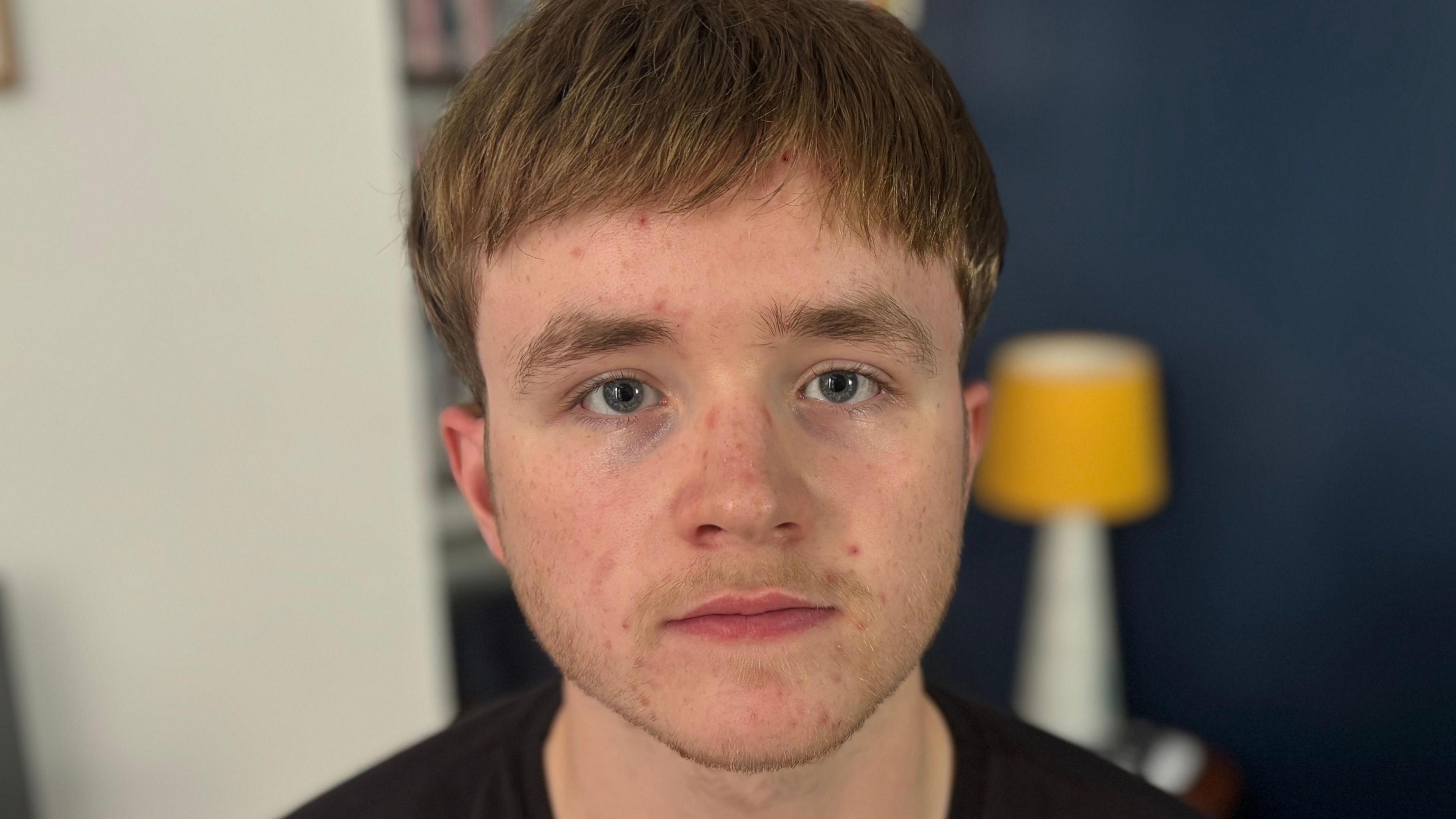 Judah Cousin looks into the camera. He has brown hair and he's wearing a black t-shirt. It is a head and shoulders shot of him.