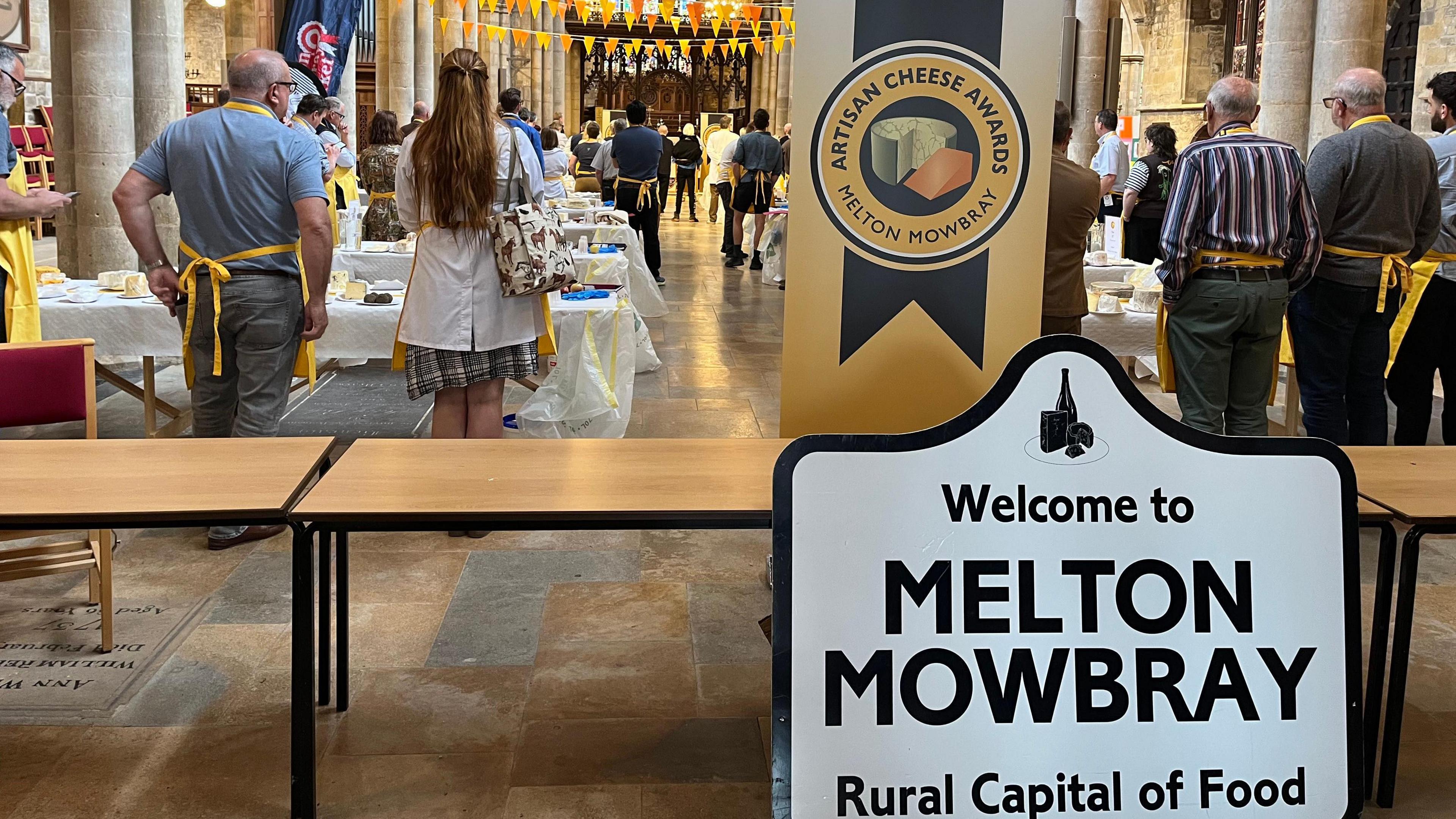 Tables of cheeses with Melton Mowbray sign in foreground