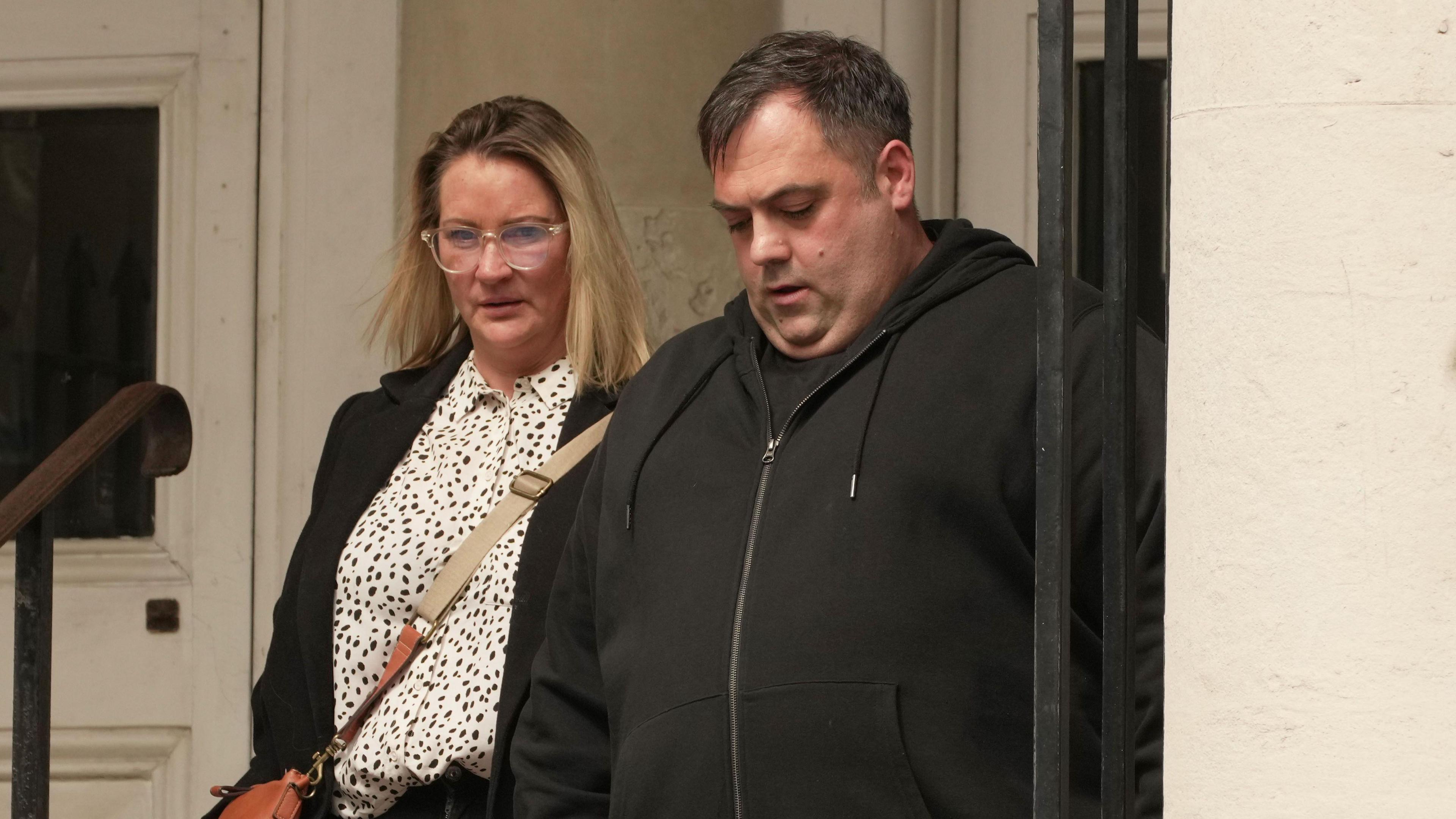 A woman walking beside a man as they leave court