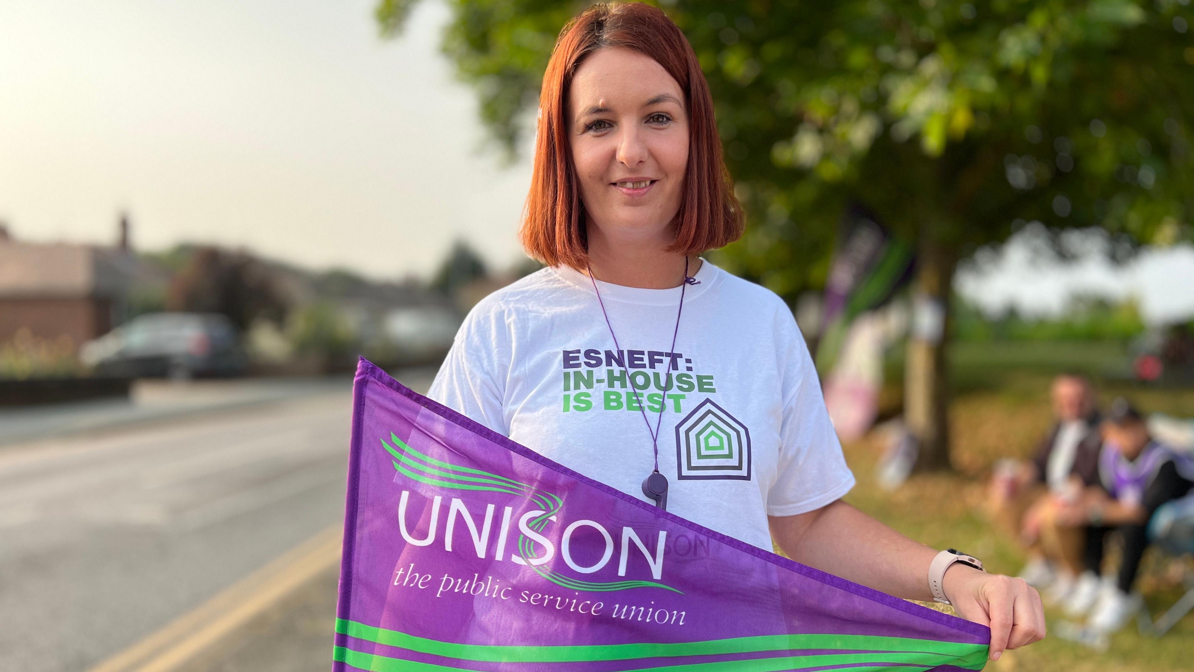 Natalia Janusz holding a flag on the picket line at Colchester Hospital