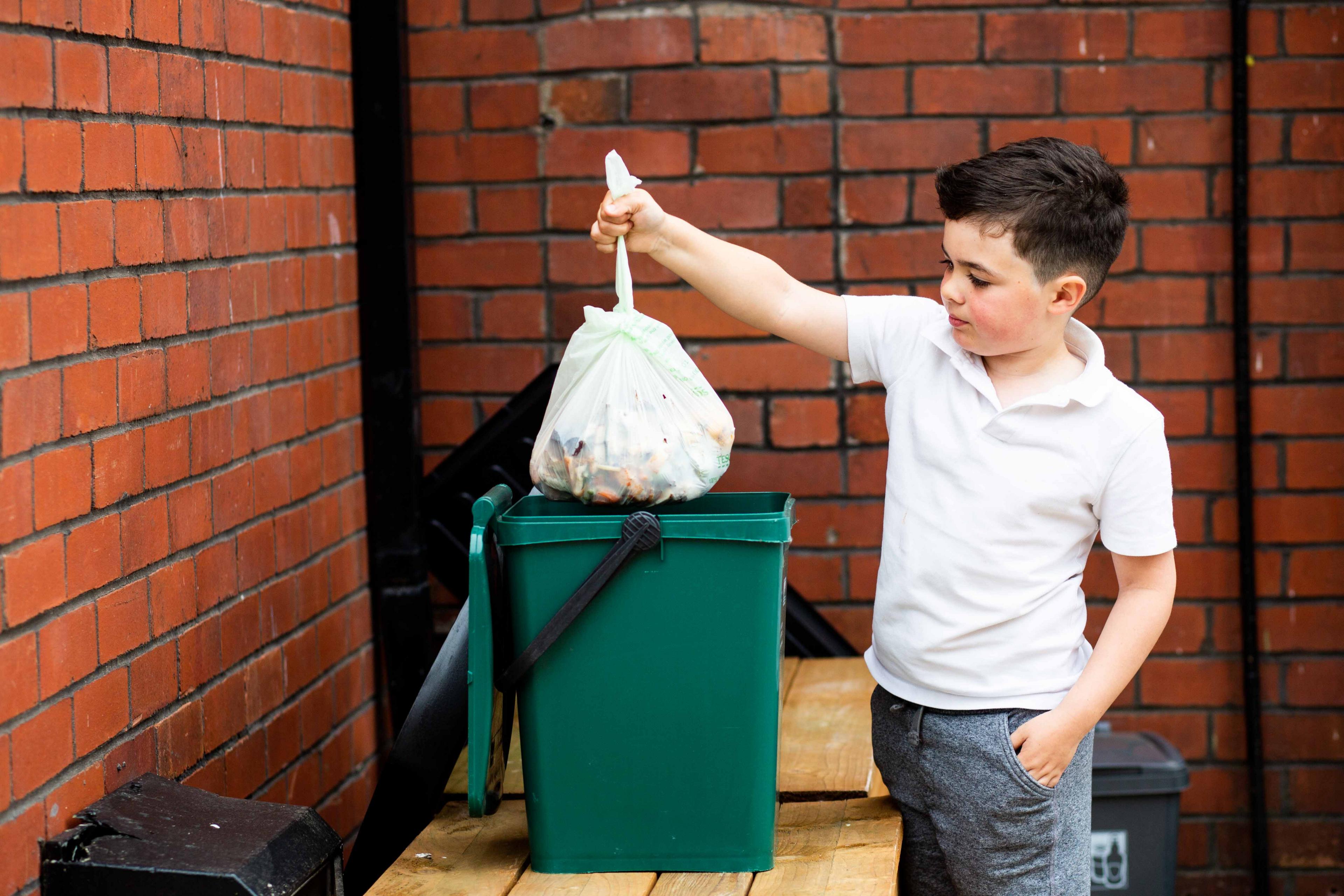 Boy puts food waste in recycling caddy