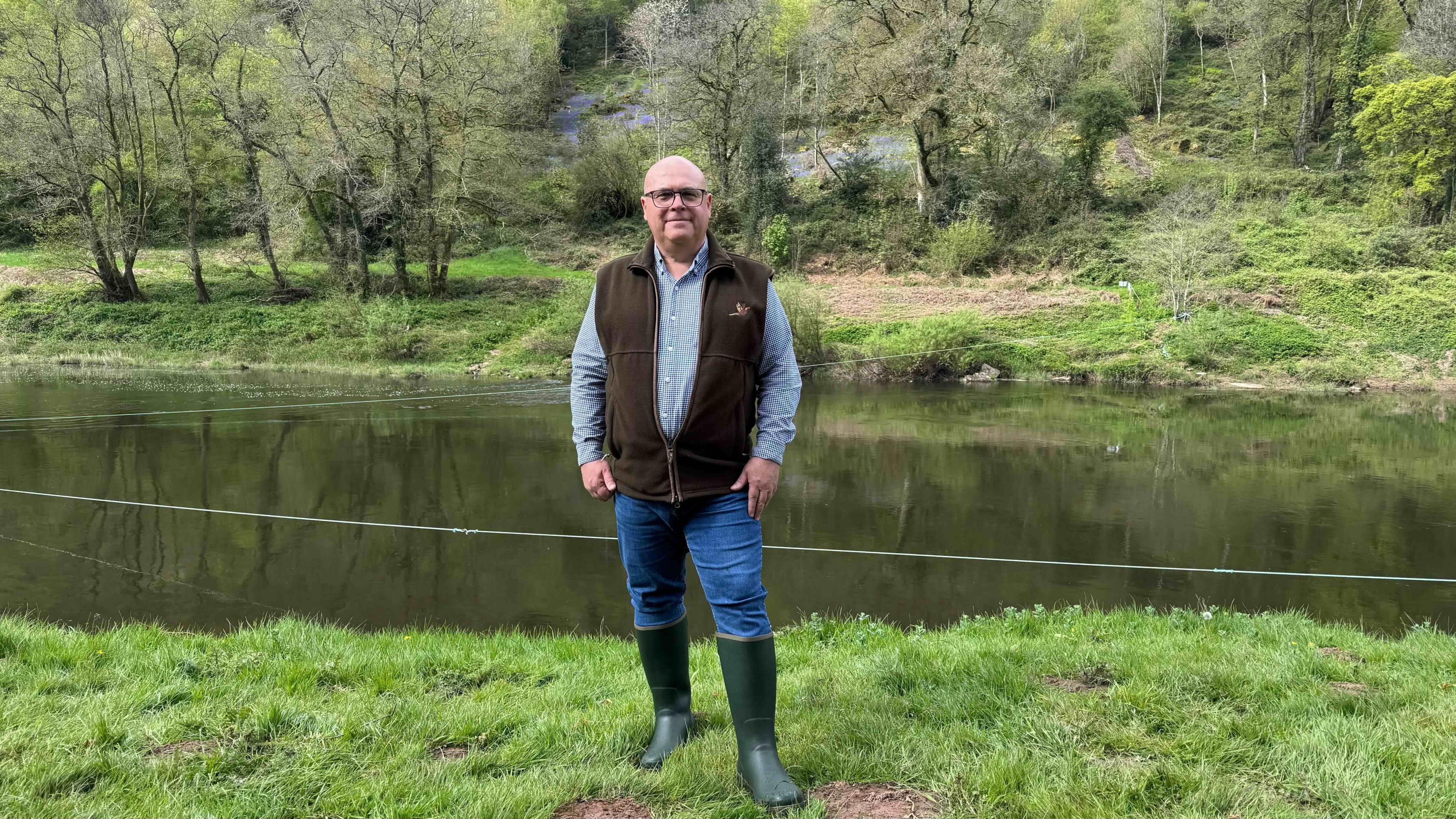 A fisherman stands on the banks of the River Wye