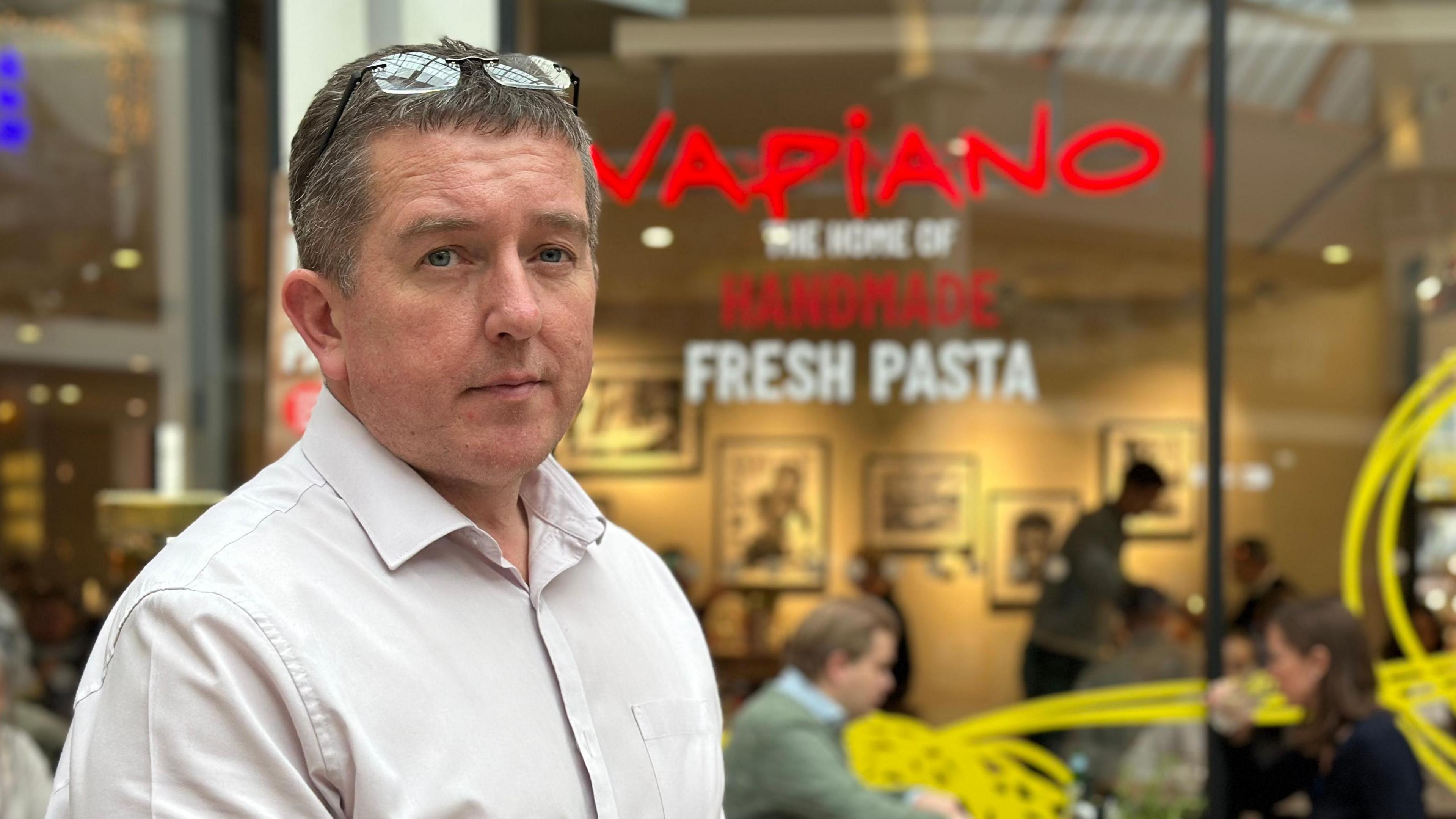 Andy Crisp standing in front of pasta and pizza restaurant, Vapiano