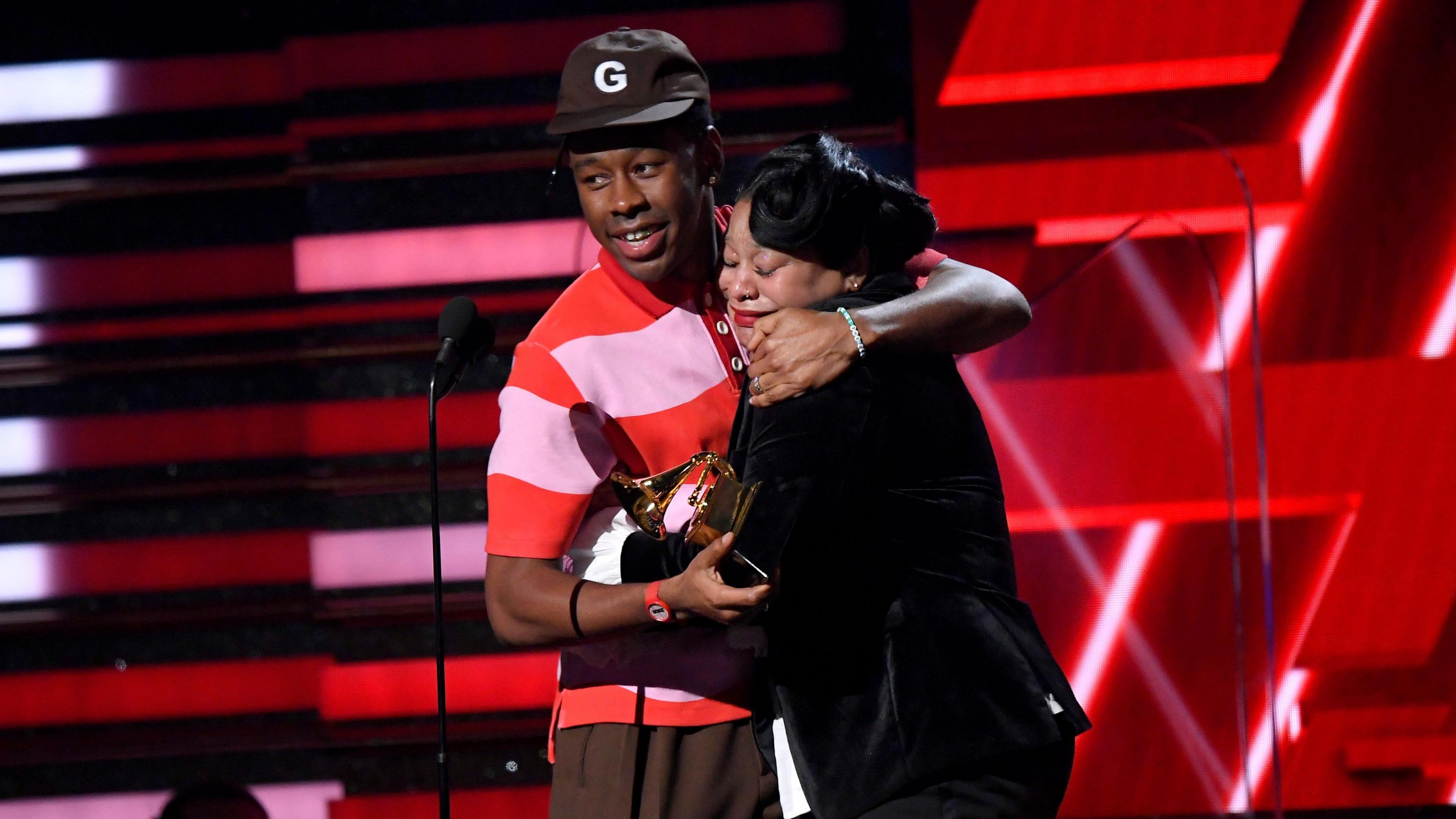 Tyler, The Creator hugging his mum on stage, while holding the Grammy for Best Rap Album.