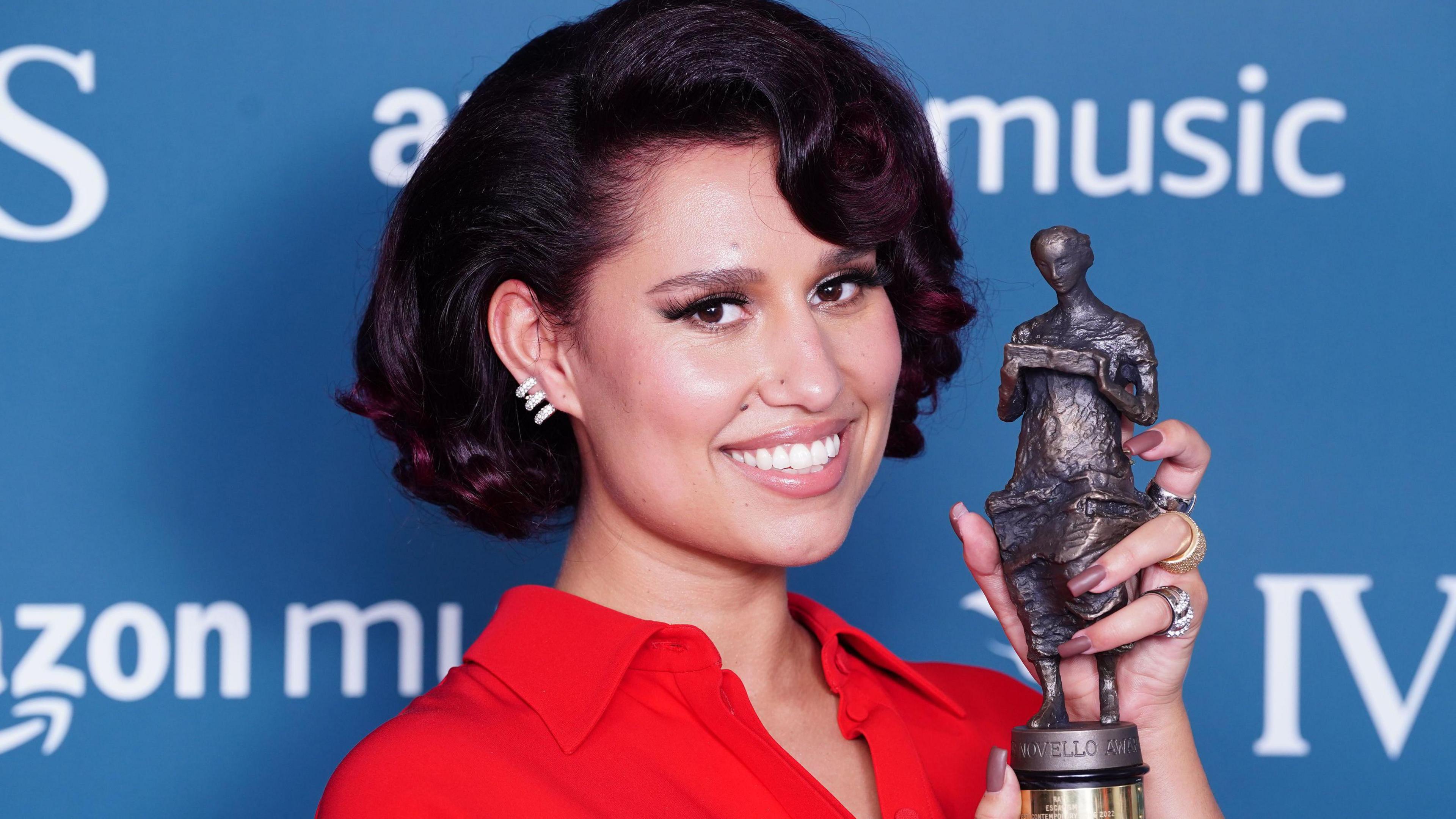 Raye holds up an Ivor Novello songwriting award