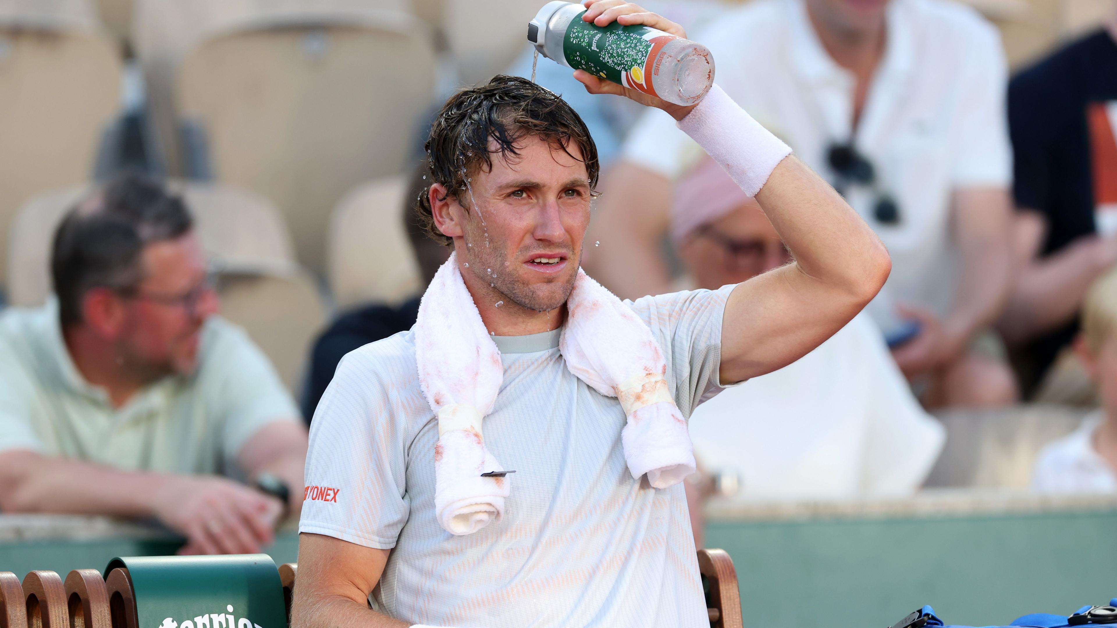 Casper Ruud pours water over his head during a change of ends